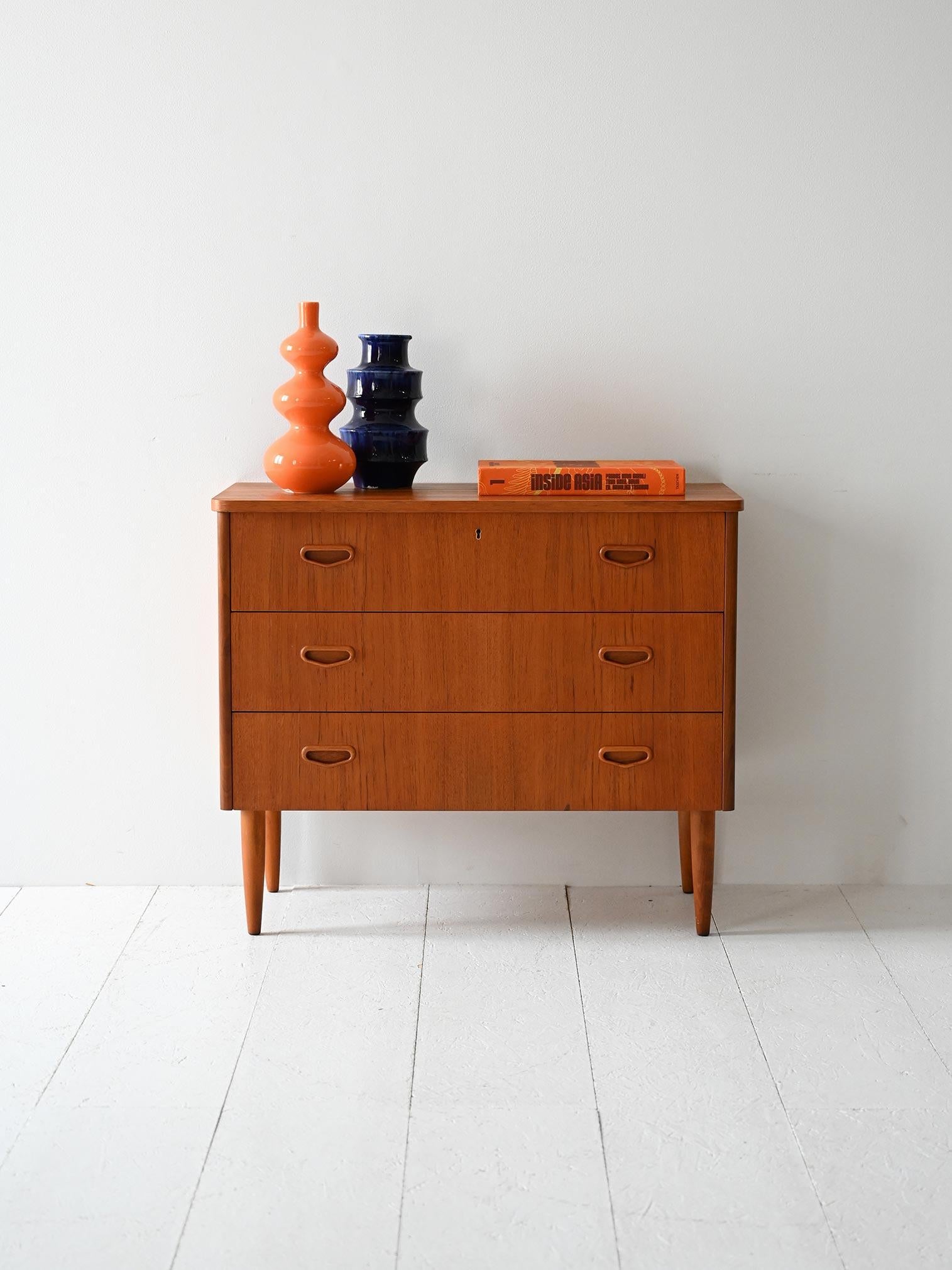 Cassettiera vintage con tre cassetti, maniglie intagliate a triangolo invertito e gambe affusolate in stile nordico.

Linee semplici e proporzioni compatte caratterizzano questa cassettiera scandinava anni ’50/’60. I tre cassetti sono arricchiti da