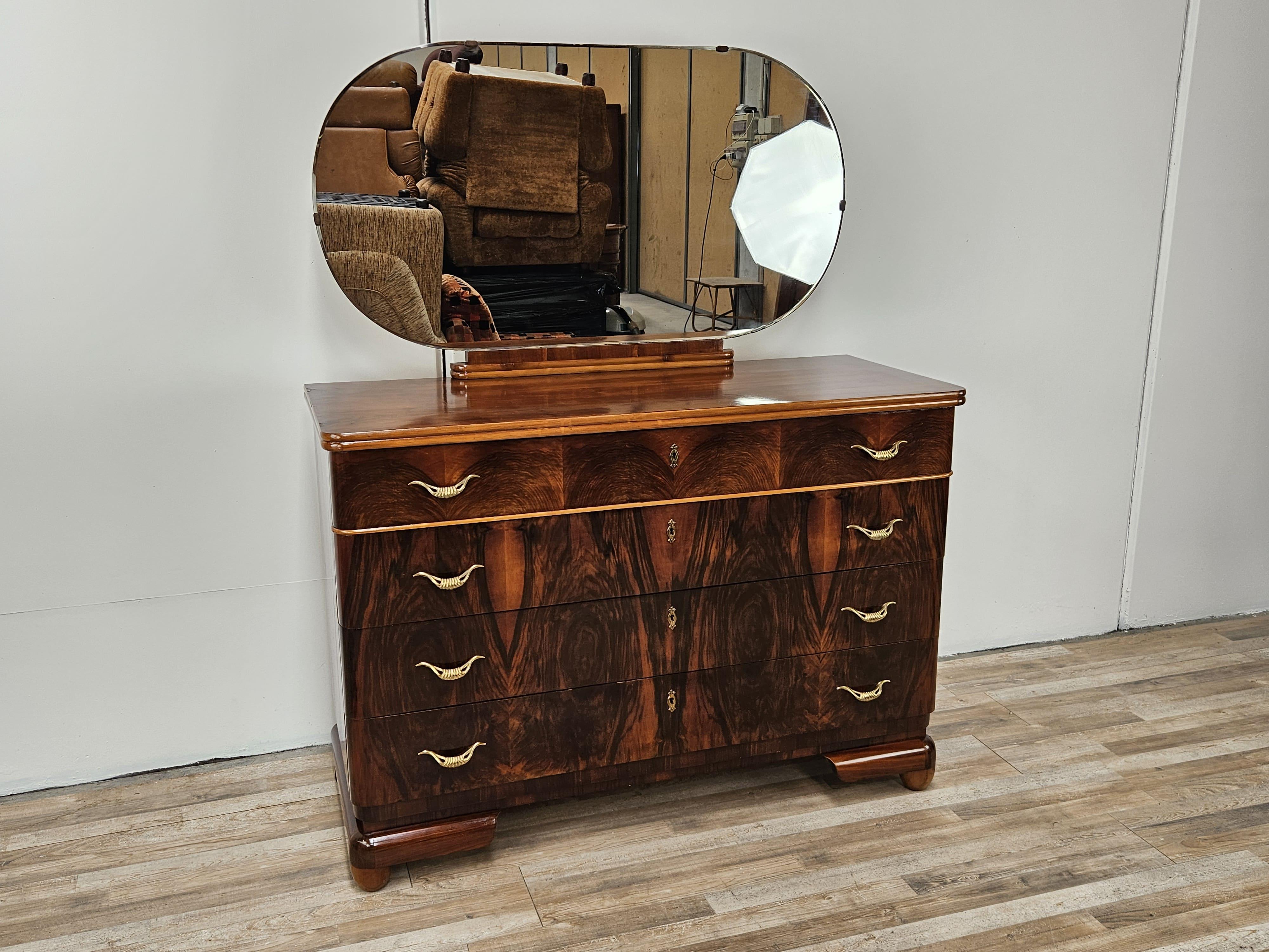 Elegante comò in radica di noce dei primi anni '40 circa, arricchito da decori e particolari in acero e da una specchiera ovale con vetro molato originale dell'epoca.

Da notare le grandi maniglie in ottone, fini ed eleganti come creano contrasto