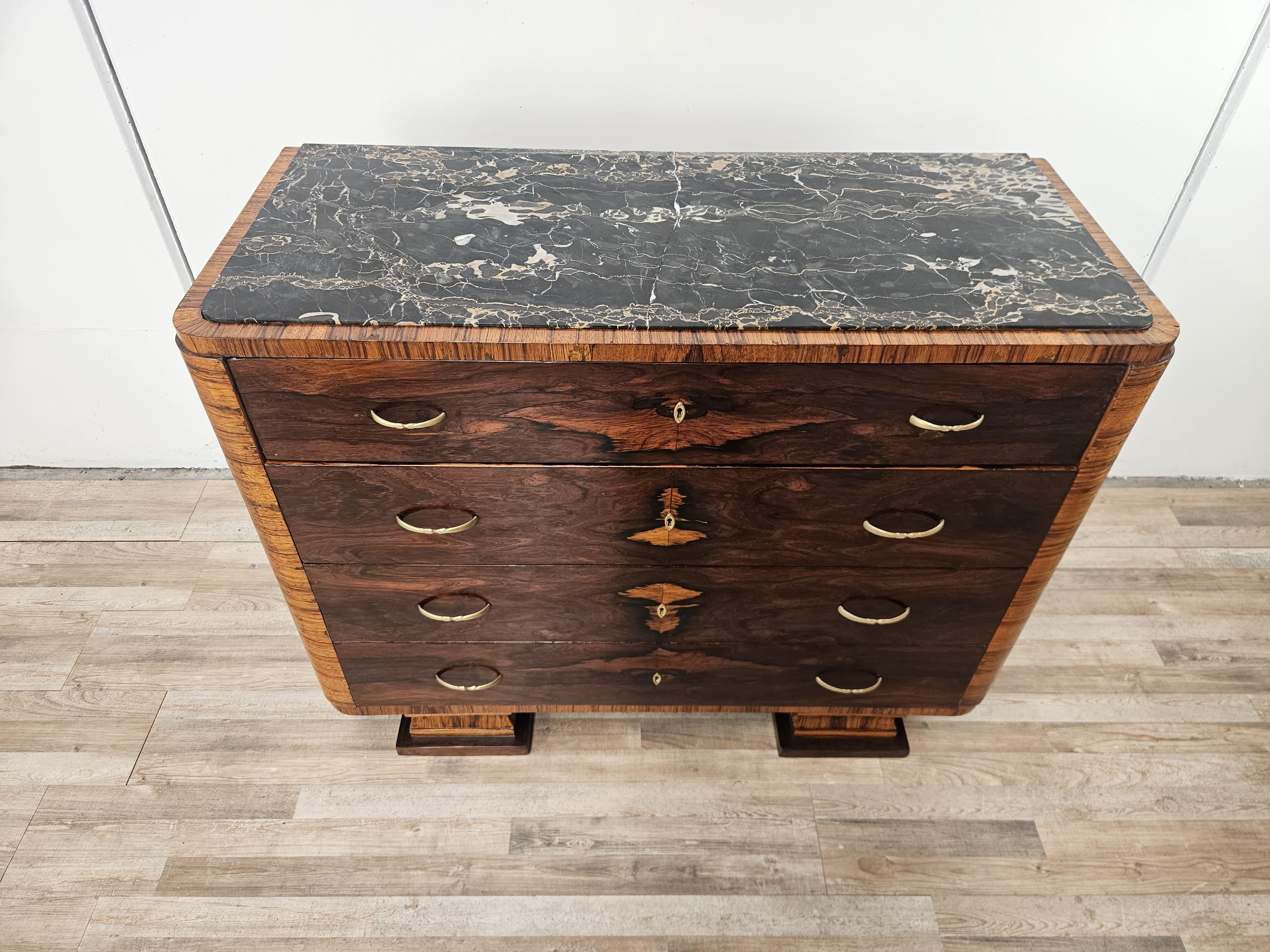 Un elegante comò Art Deco dei primi anni '40 in radica e piuma di mogano con maniglie in ottone e una bellissima lastra di marmo vintage.

Dotato di quattro cassetti grandi e robusti, si adatta perfettamente a qualsiasi arredamento grazie alla linea