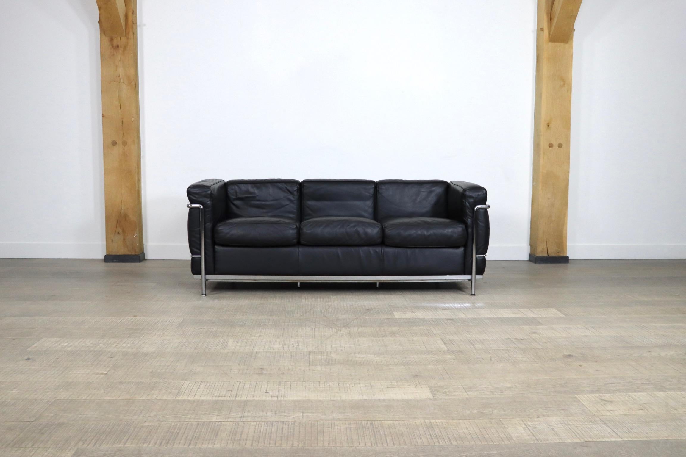 Stunning LC2 three seater sofa, a true design classic by Le Corbusier, Pierre Jeanneret and Charlotte Perriand originally designed in 1928. The modern sofa is composed of a tubular chrome frame and high-end black leather cushions. The sofa is signed