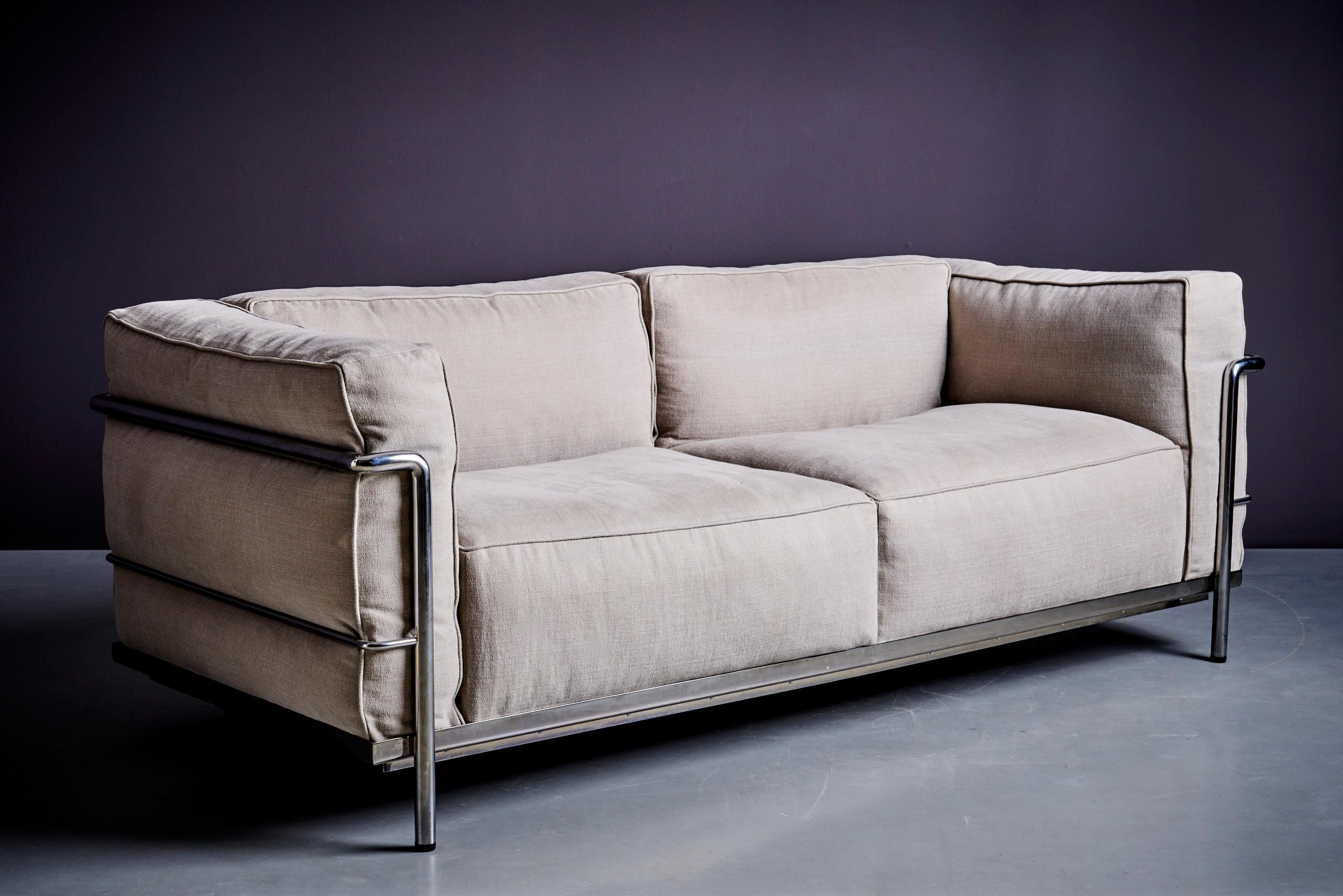 The Cassina LC3 Sofa, designed by Le Corbusier, Pierre Jeanneret, and Charlotte Perriand in 1928, is a modern classic. It features soft, feather-down cushions and a sturdy chrome-plated steel frame. The upholstery is high-quality **Category F