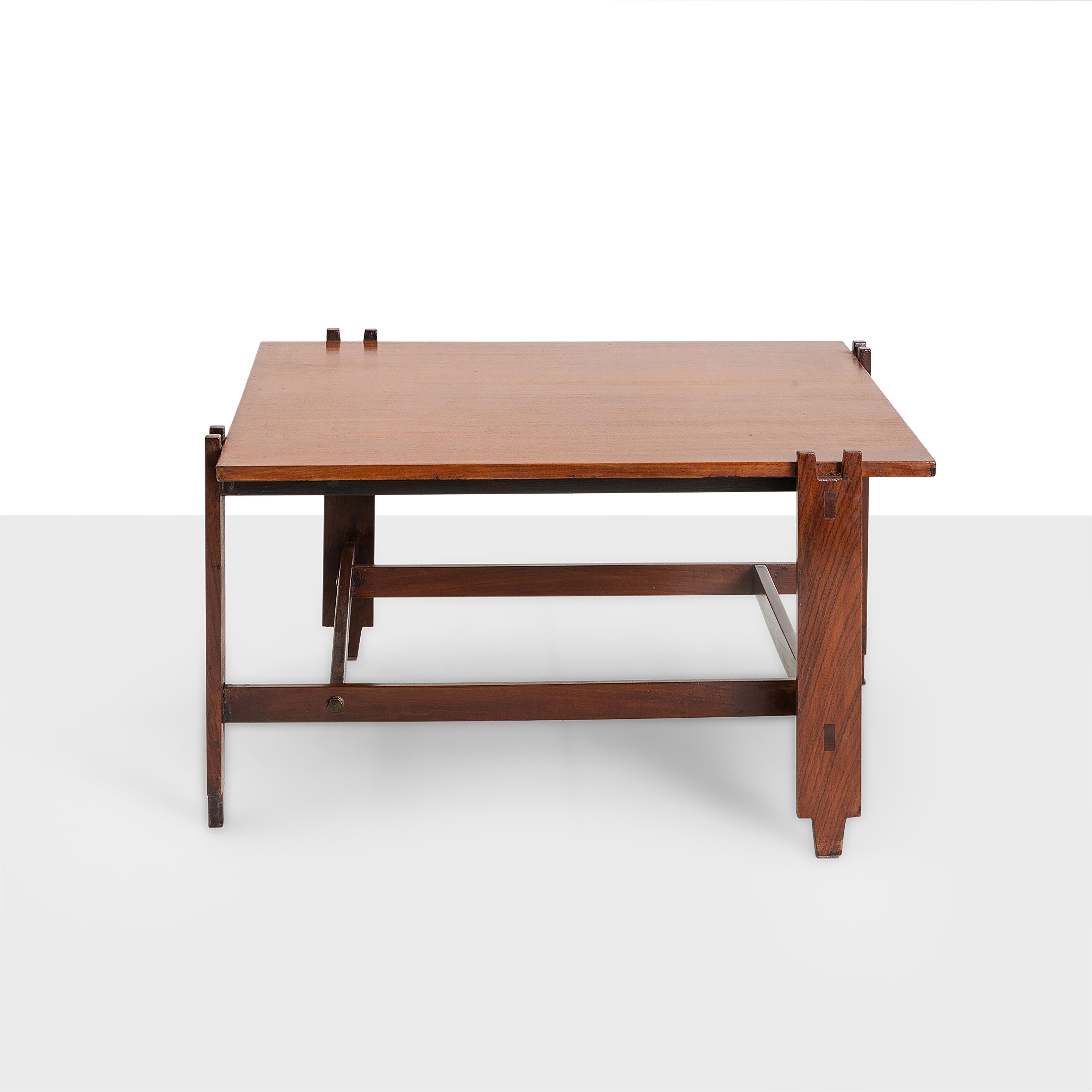 1960s Cassina wooden table with a square base and staggered inserted legs. It is a low table that can be used in different rooms and occasions. The Italian manufacturer Cassina is famous for its versatile tables with distinctive shapes, easily