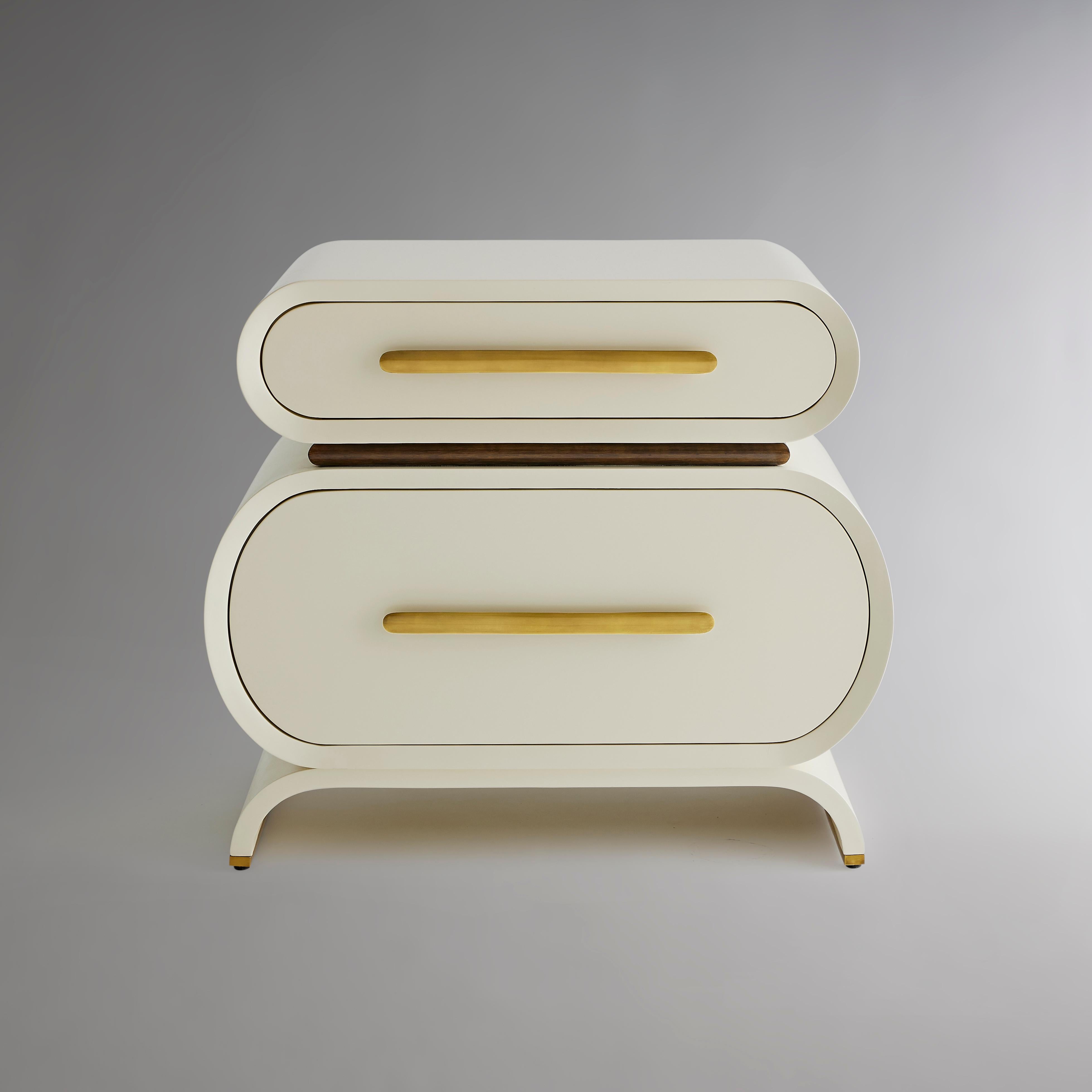 Two curved wood-cased drawers in our medium sheen lacquer separated by a divide of Eucalyptus in a coffee bean finish stand atop a base that repeats the angle of curve as it rounds into feet lined in burnished brass. The collection’s signature