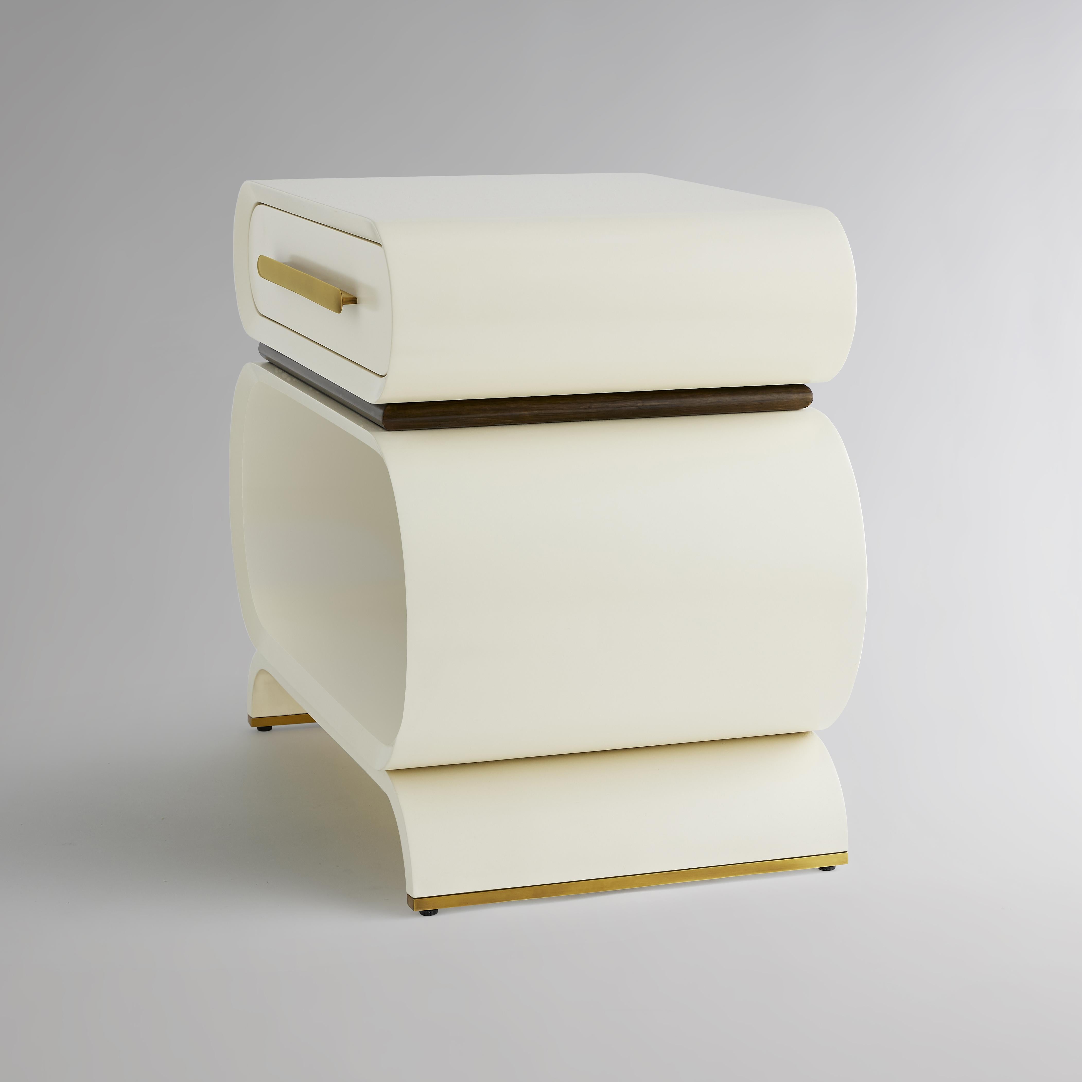 Two curved wood-cased drawers in our medium sheen lacquer separated by a divide of Eucalyptus in a coffee bean finish stand atop a base that repeats the angle of curve as it rounds into feet lined in burnished brass. The collection’s signature