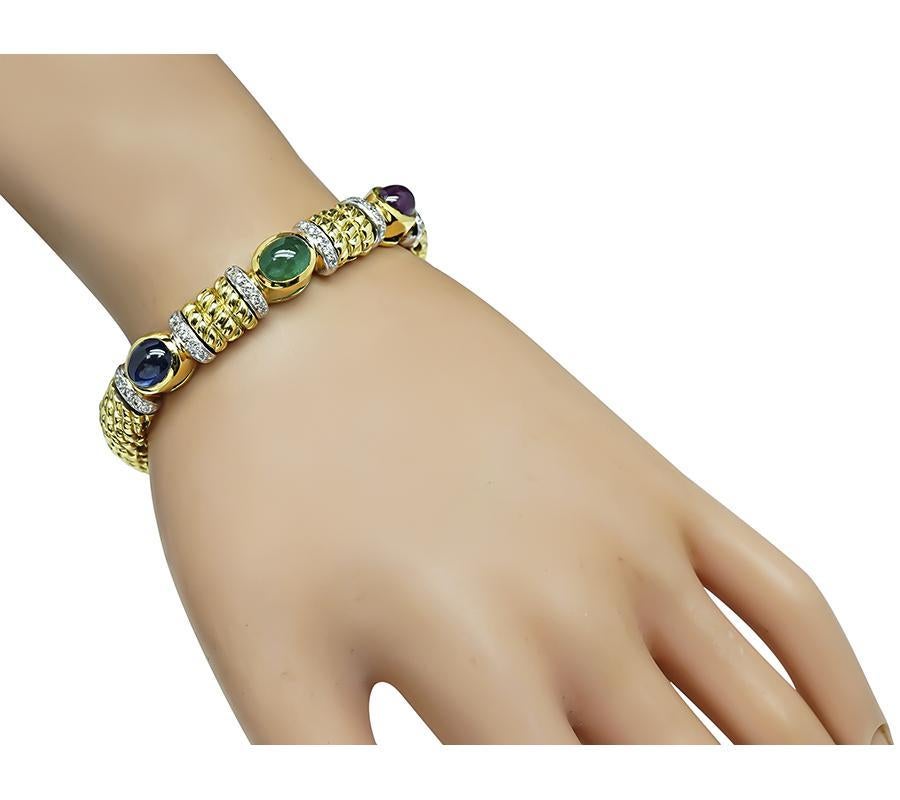 Voici un élégant bracelet Cassis en or jaune et blanc 18 carats. Le bracelet est serti de jolis saphirs, émeraudes et rubis cabochons qui pèsent respectivement environ 3,50ct, 2,50ct et 3,50ct. Le poids total des pierres est d'environ 9,50 ct. Les