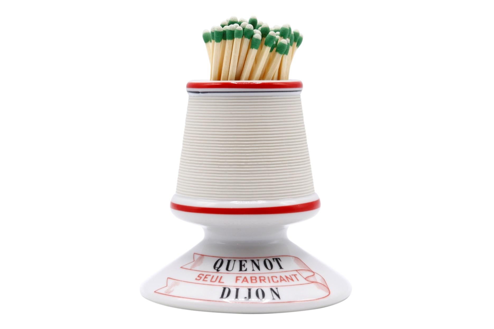 A Parisian café ceramic match striker and holder. Decorated with a red line around the top and middle, with red and black writing on the base.
