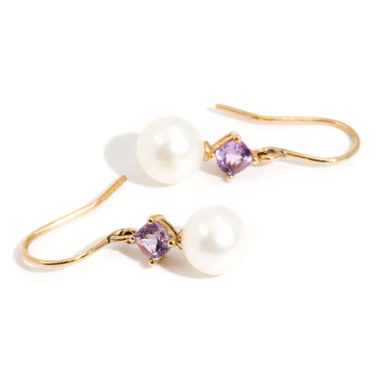 Crafted in 9 carat yellow gold are these vintage drop earrings featuring two gorgeous 7.9 millimetre lustrous freshwater pearls paired with two bright purple cushion cut Amethysts.  We have named these charming vintage earrings the Cassy Earrings.