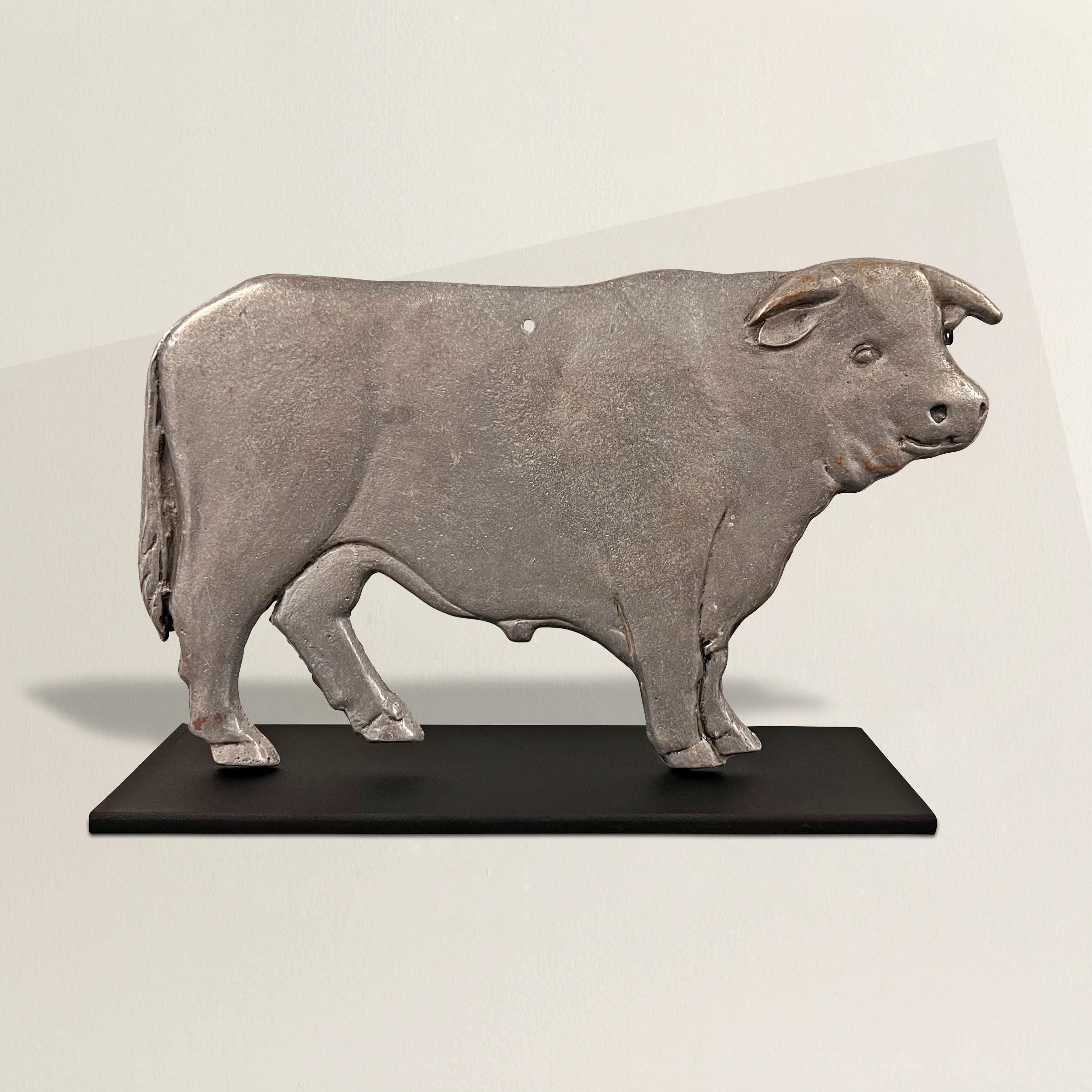 A charming early 20th century American cast aluminum bull plaque from a butcher's shop, now mounted on a custom steel stand so it can be displayed anywhere in your home.