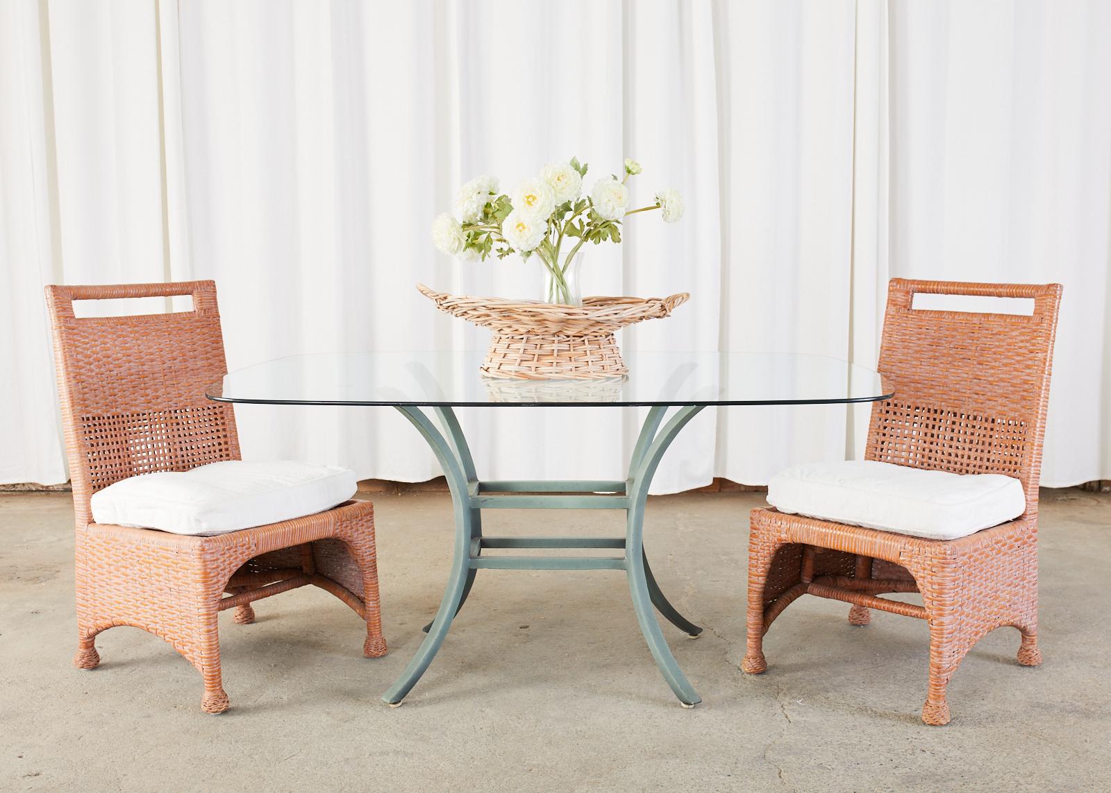 Oval glass garden or patio dining table featuring an aluminum base with a faux verdigris finish. Crafted from four gracefully curved legs conjoined in the middle with two stretchers. The table has a simple and elegant profile.
