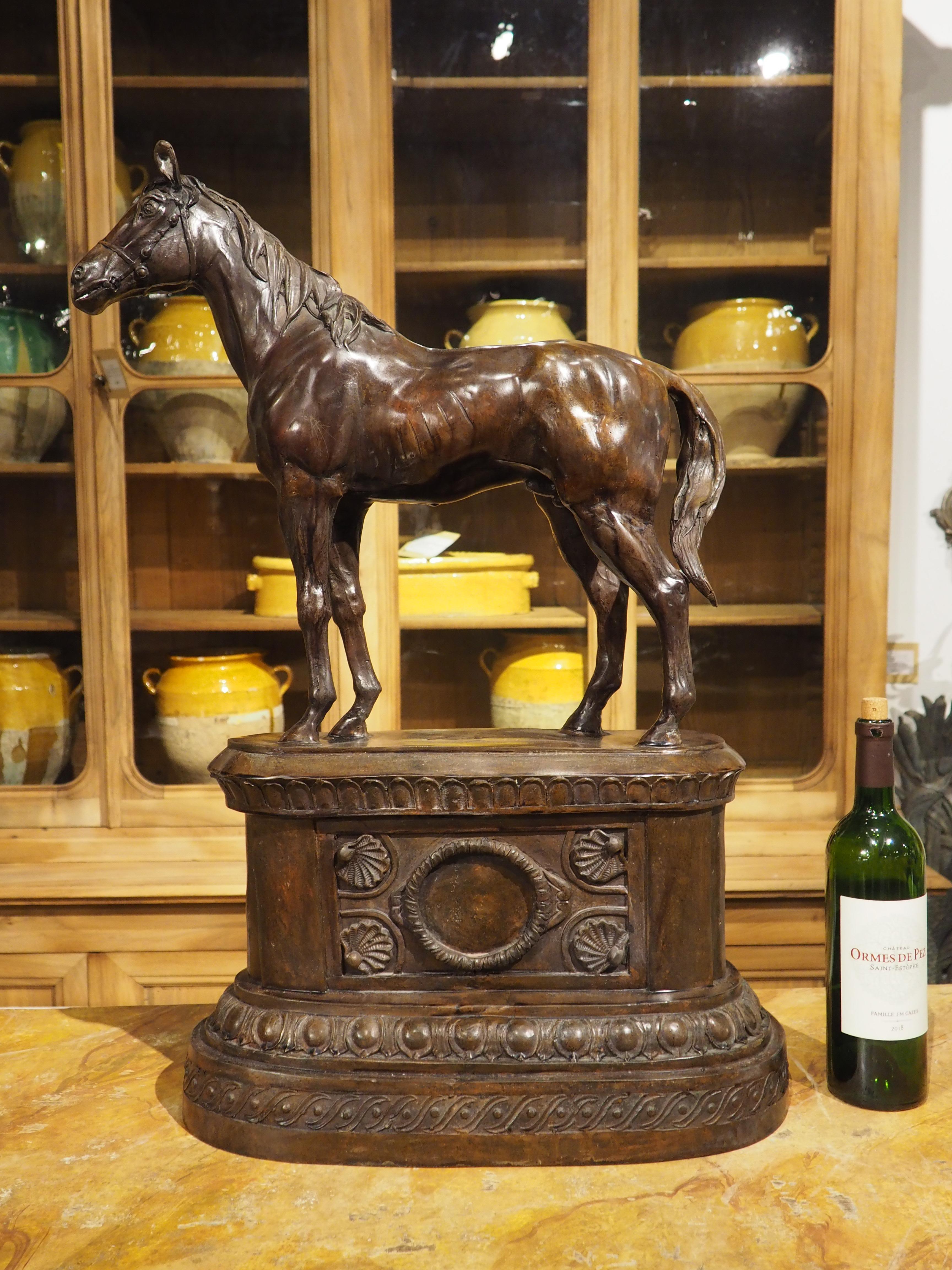 Cast in the 1900s, this bronze sculpture of a horse on a pedestal has a lovely patination that accentuates the standing stallion. Clad with a bridle and bit, but no other dressing, the majestic horse has a long, flowing mane that lays flat as he