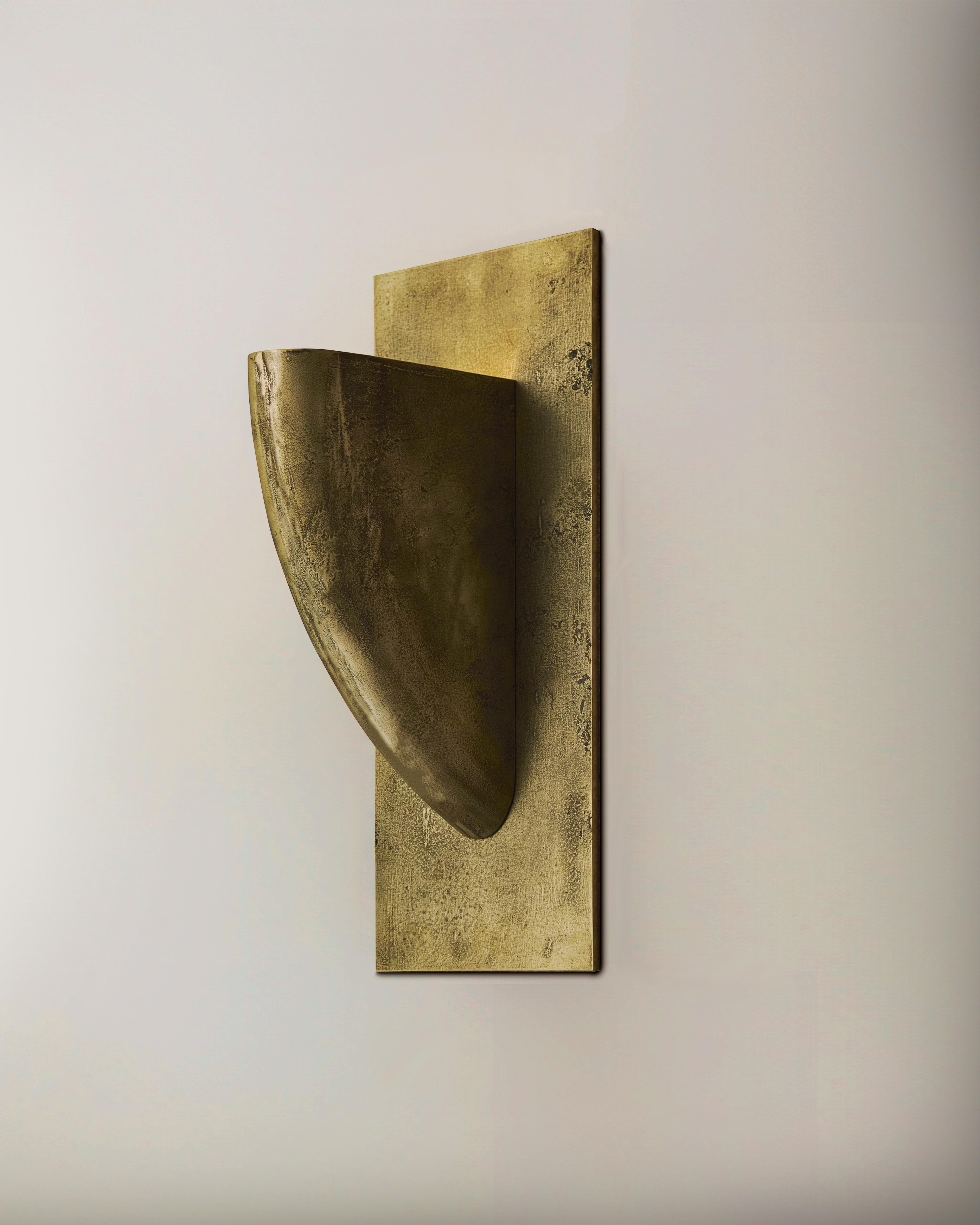 Una scultura illuminata in metallo sabbiato sospesa a parete con bordi lucidi. L'applique, che può essere installata verso il basso o verso l'alto, è composta da un solido elemento strutturale in metallo fuso a sabbia che si illumina all'interno