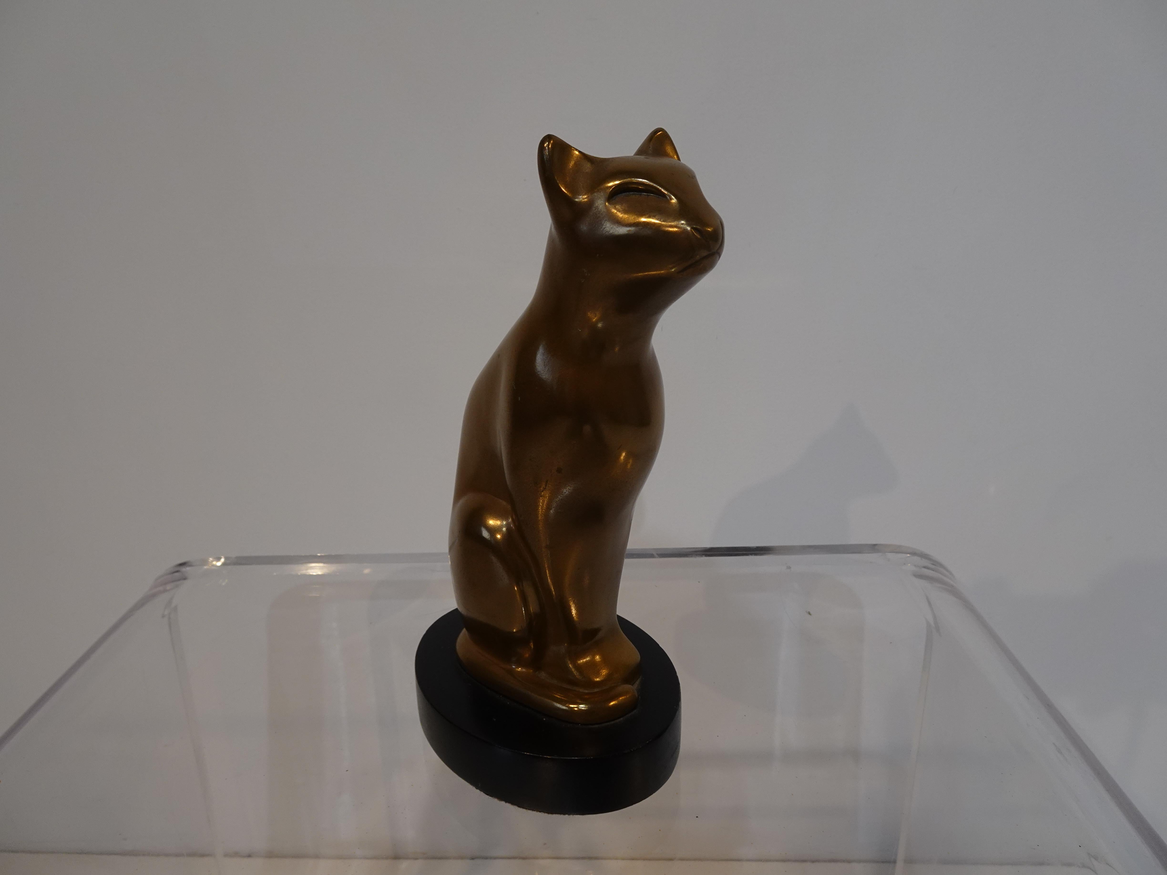 A very nice mid century cat sculpture cast in brass sitting on an oval satin black wood base, to the lower edge of the piece is the cast signature of the artist Dewitt.