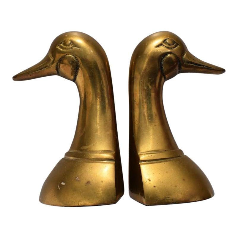 A pair of two cast brass duck heads or mallard head bookends. Each bookend is cast in brass into the shape of a mallard or duck bust. Carvings of eyes, cheeks and beaks give this pair the touch of animalia that every room or bookshelf needs. This