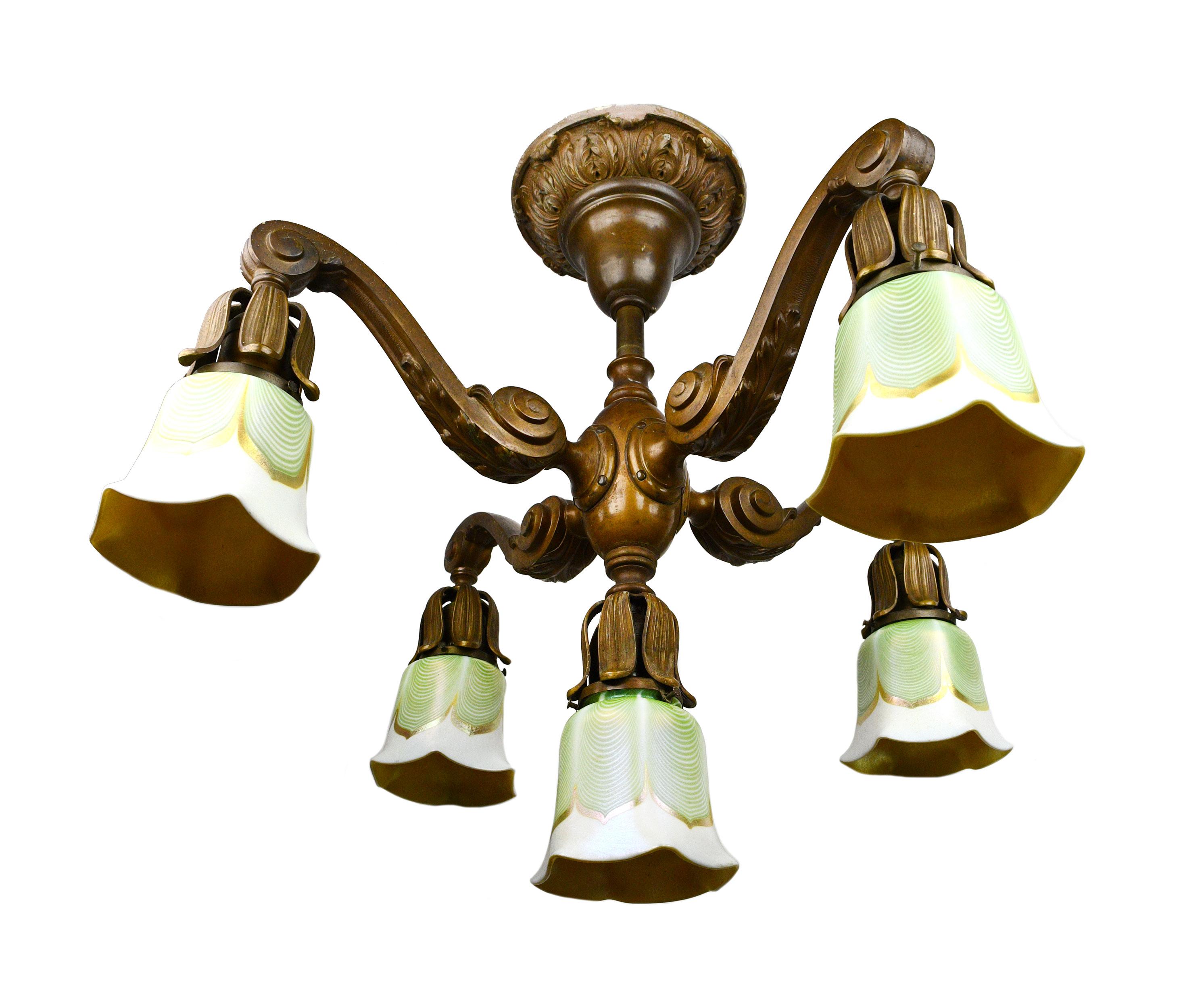 This amazing cast bronze five-light chandelier is complete with Lustre Art shades. A heavy cast ring of acanthus leaves grounds this light to the ceiling. The strong vertical line of the central light is balanced by its outstretched arms. Volute