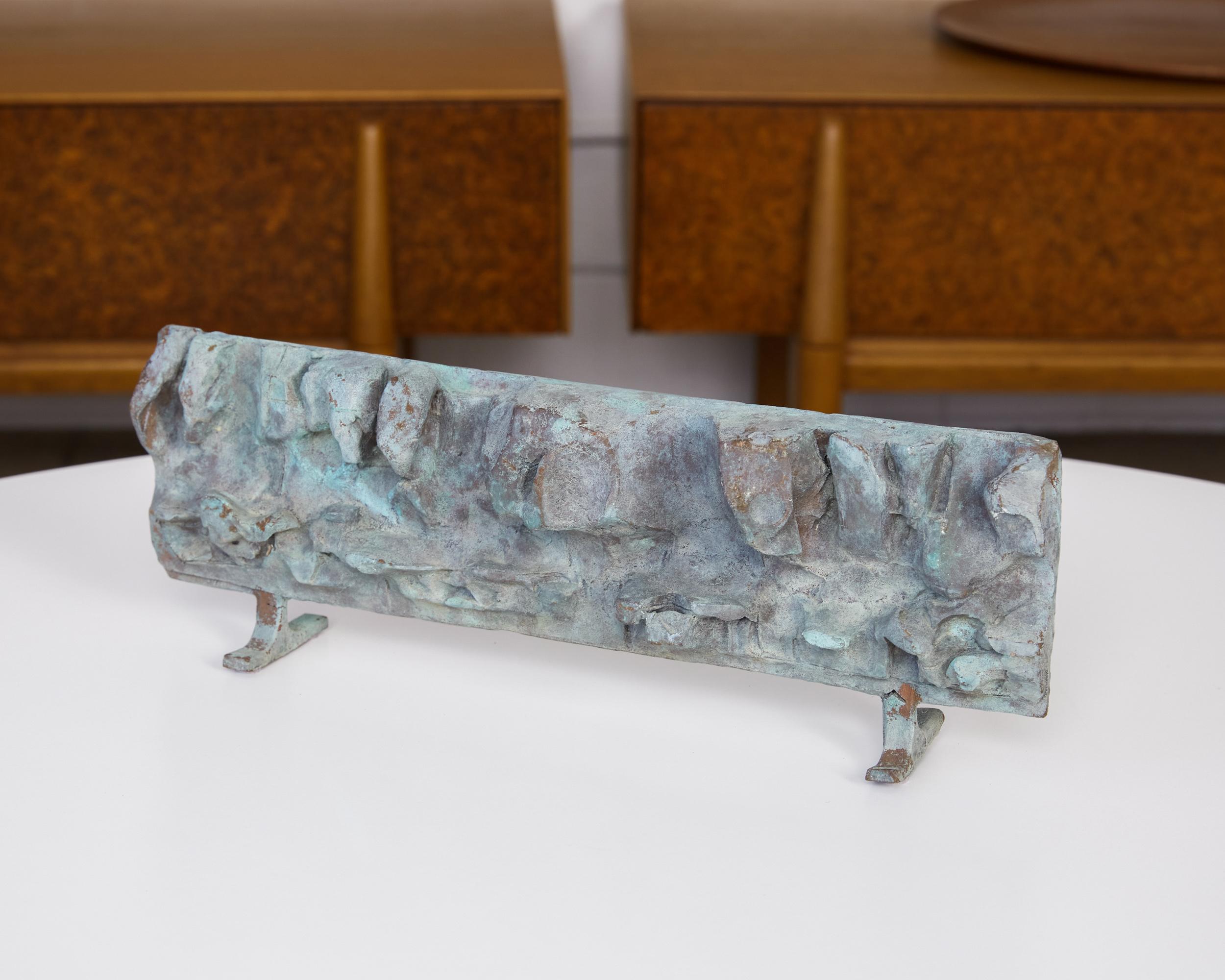 Cast bronze abstract sculpture with verdigris patina. This textured horizontal sculpture sits atop two petite perpendicular flat bar feet. It looks to be a smaller representation of a larger work, perhaps a maquette for a large sculpture or