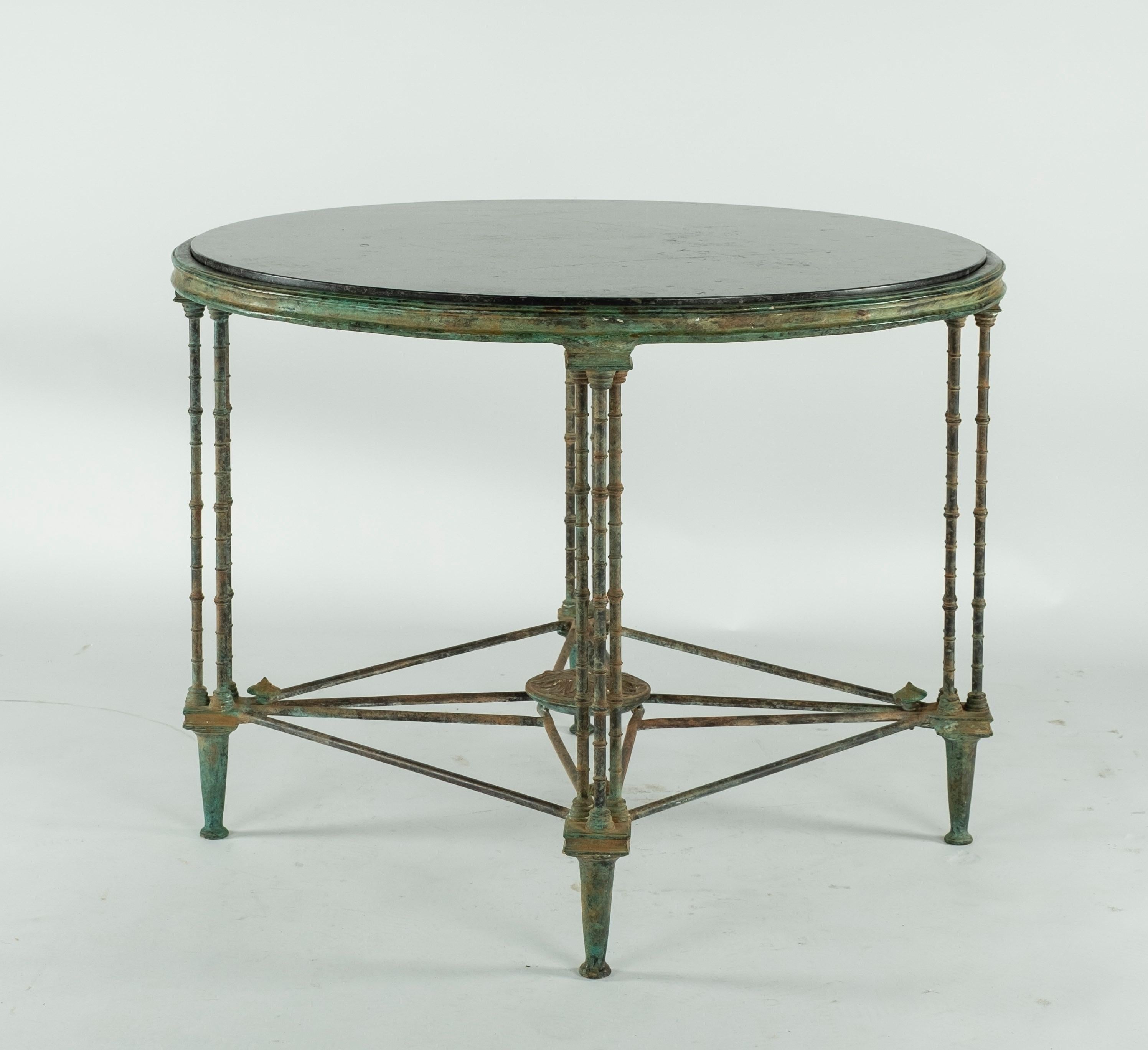Intricate cast bronze table base with four legs and a black stone marble top. Beautiful patina on the bronze. Pair of this table is available.