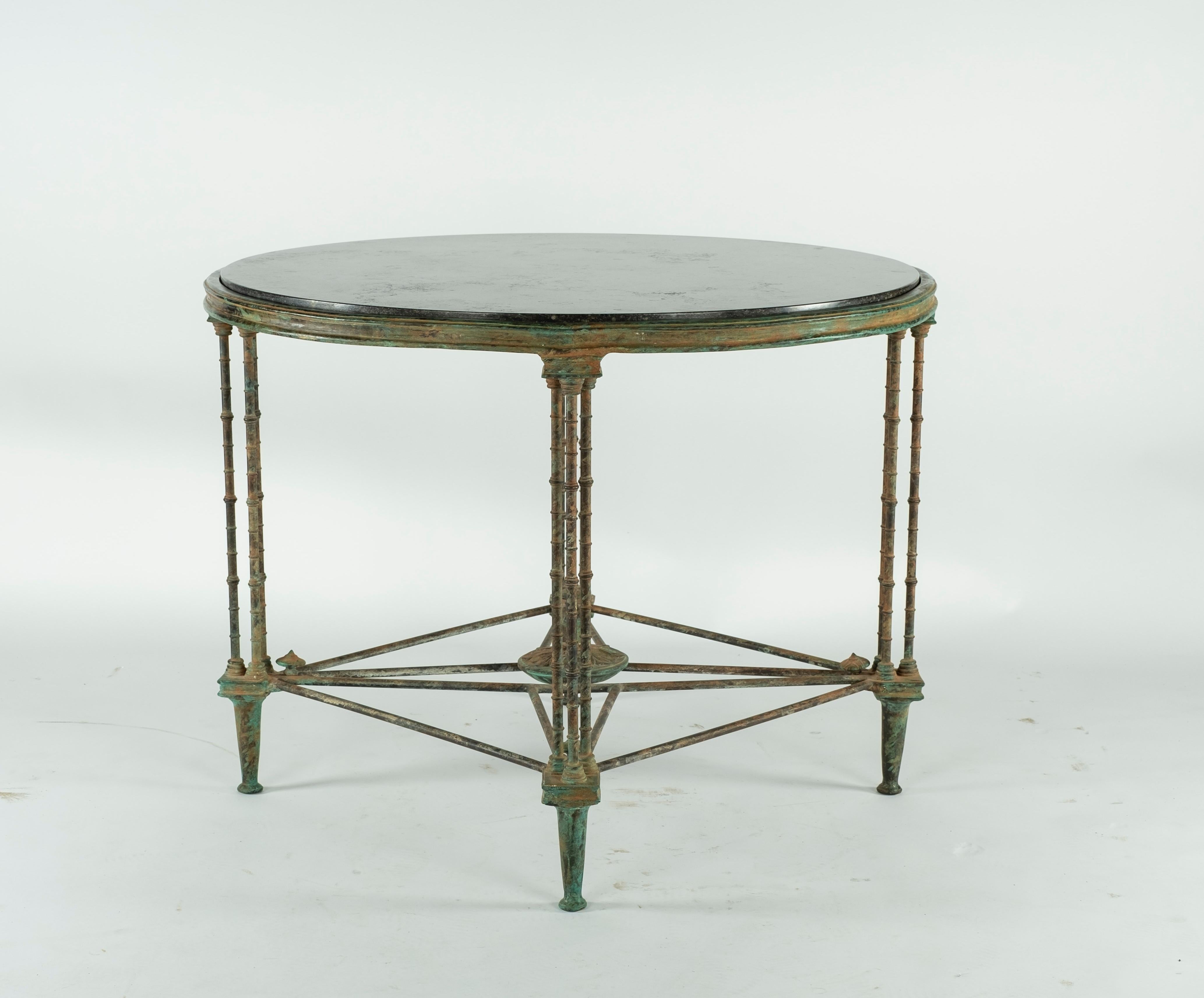 Intricate cast bronze table base with four legs and a black stone marble top. Beautiful patina on the bronze.