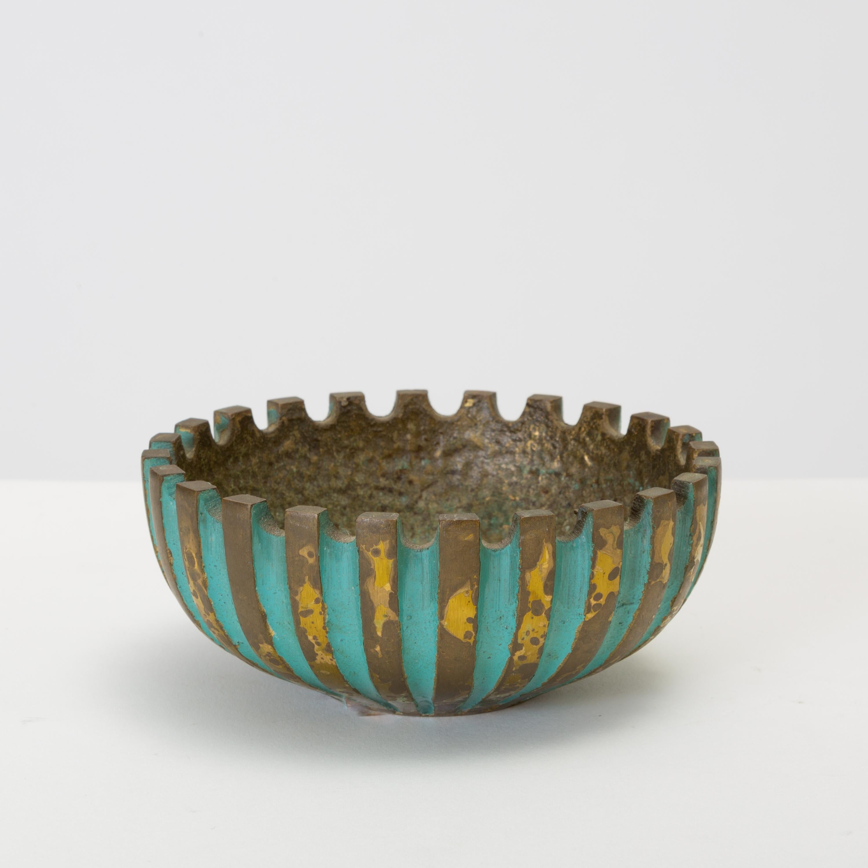 A heavy, cast bronze ashtray by Oppenheim of Israel. The bowl-shaped piece has a ridged construction with a scalloped edge and a hammered well. The concave portions of the fluting are finished with a verdigris patina that typifies Israeli decorative