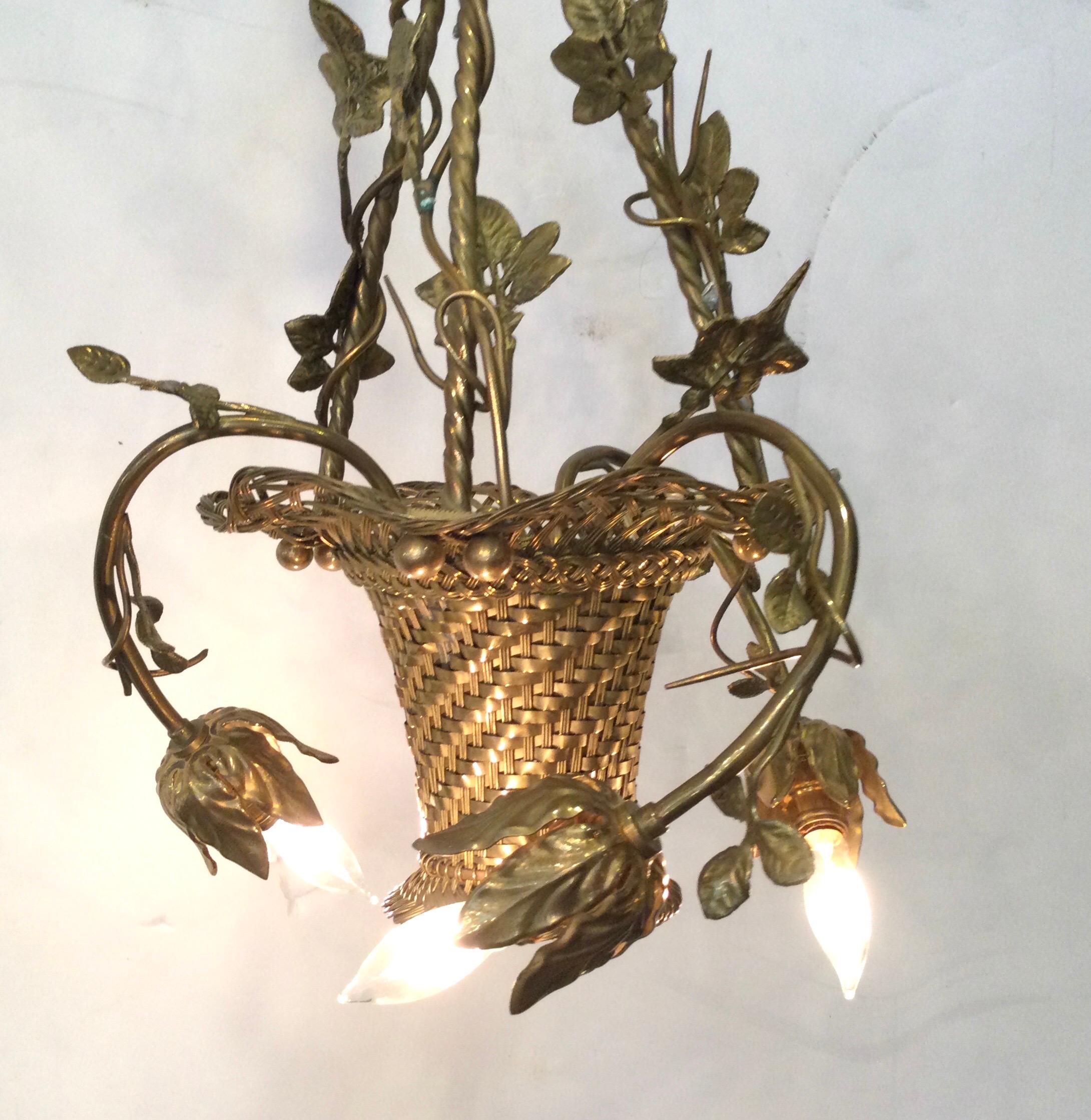 A Diminutive basket motif chandelier with three lights. The woven metal basket with thee shapely arms ending in a leafy socket for the bulb. The gilt finish is nicely aged and more dull subdued gold. Newly rewired. 39 inch drop.