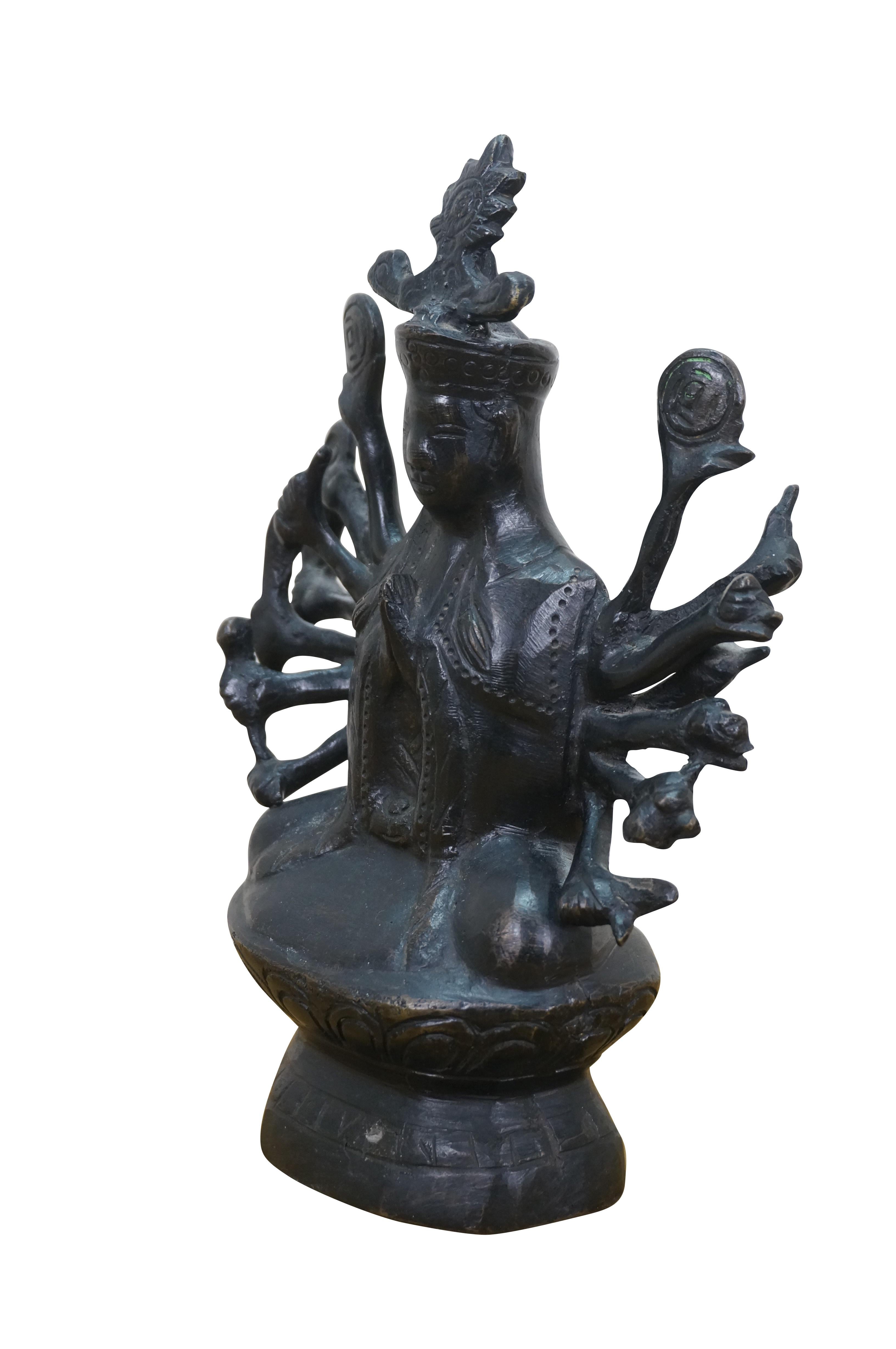 Statuetta in bronzo d'epoca del bodhuisattva buddista Avalokiteshvara, detto anche Guanyin delle Mille Braccia. Realizzata in bronzo patinato scuro, la figura è seduta in posizione di loto su una base a piedistallo, vestita con abiti e testa a forma