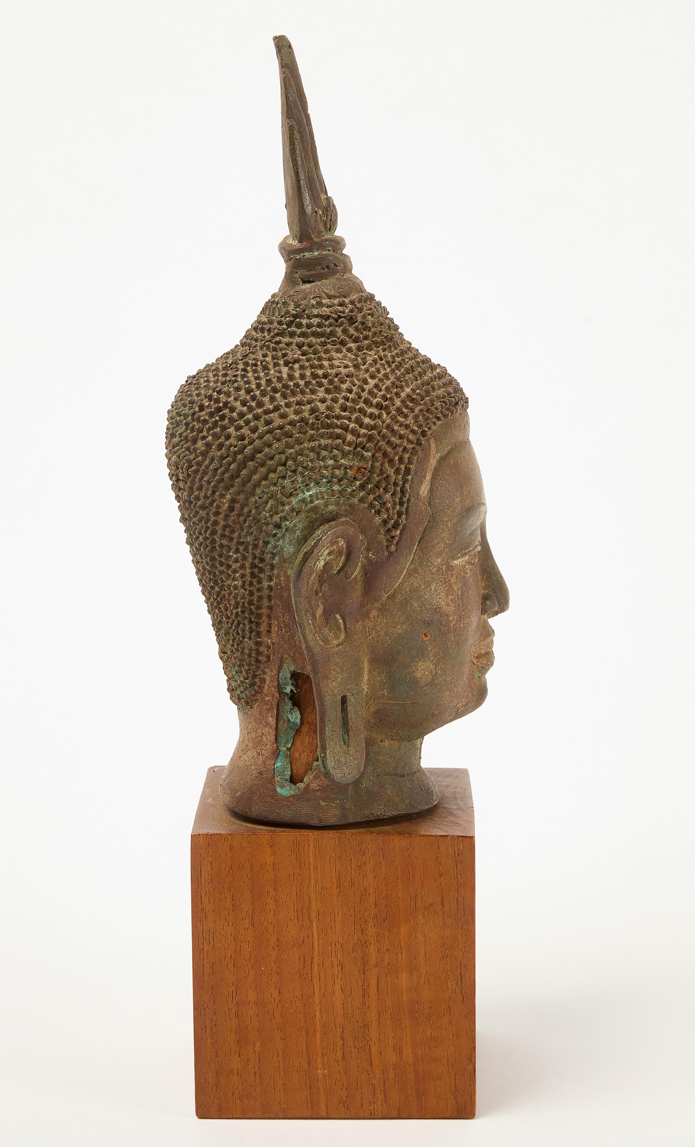 Cast bronze Buddha head. On a carved wooden pedestal. Circa 1890.

H 13-3/4