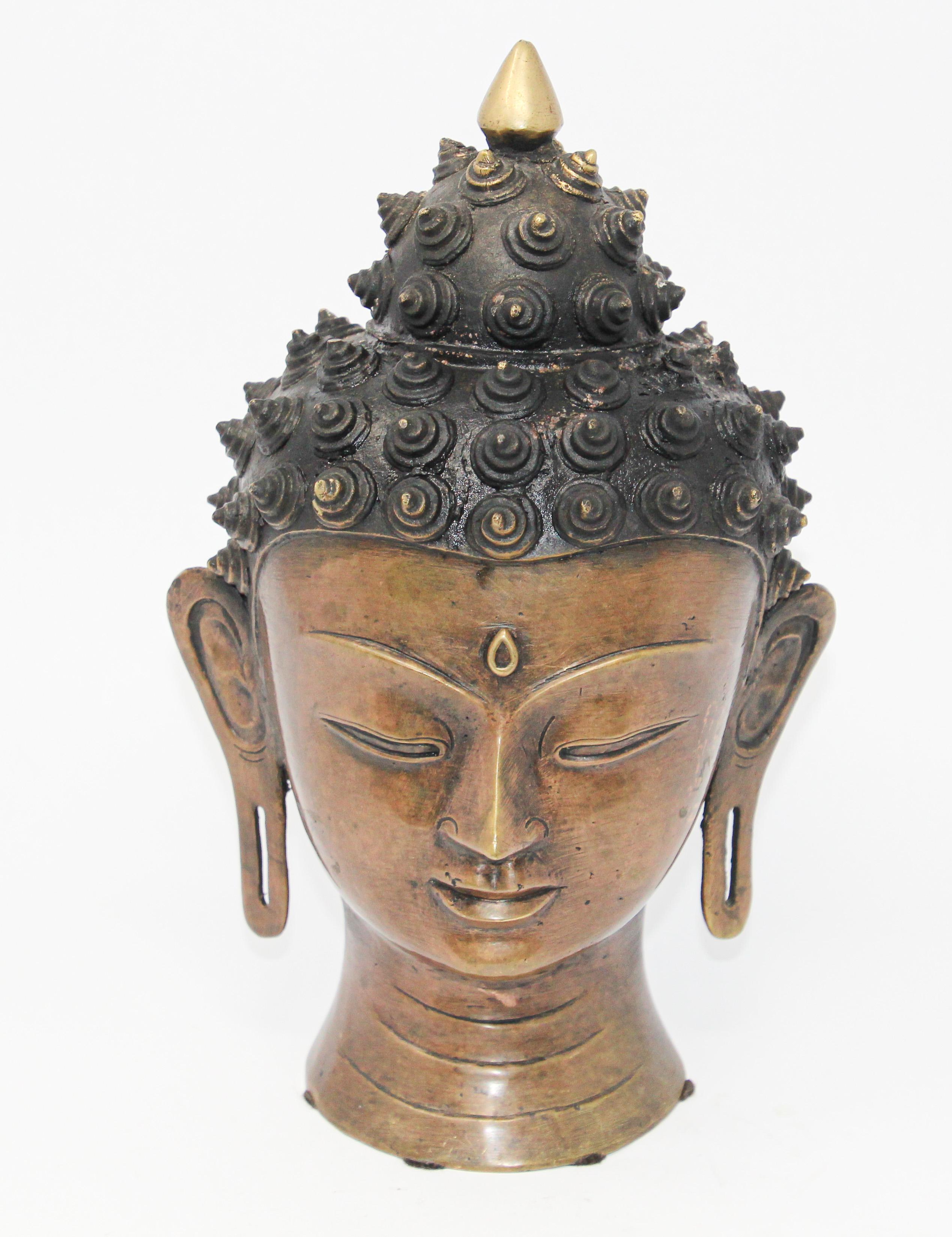Cast bronze Buddha head.
Buddha head with eyes lowered in meditation, serene and calm, representing the enlightened Buddha.
Finely modeled with incised chin, elongated eyes and gently arching brows, flanked by pendulous earlobes, the hair in tight