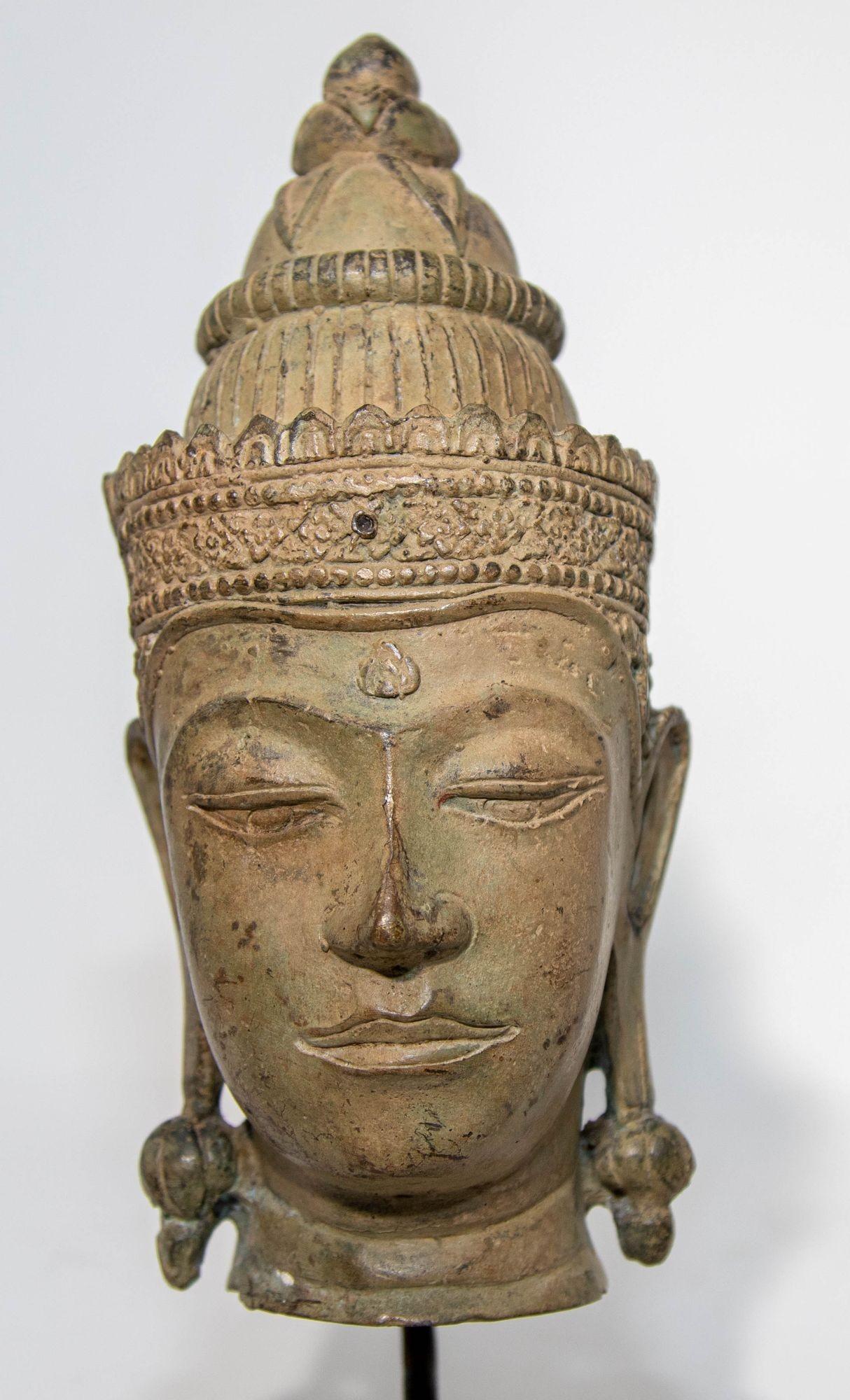 Antique Southeast Asian cast bronze buddha head sculpture with verdigris patina mounted on a ebonized wood base.
Bronze Sukhothai style Buddha bronze head with green patina, from North Thailand.
The head is sensitively rendered with a softly