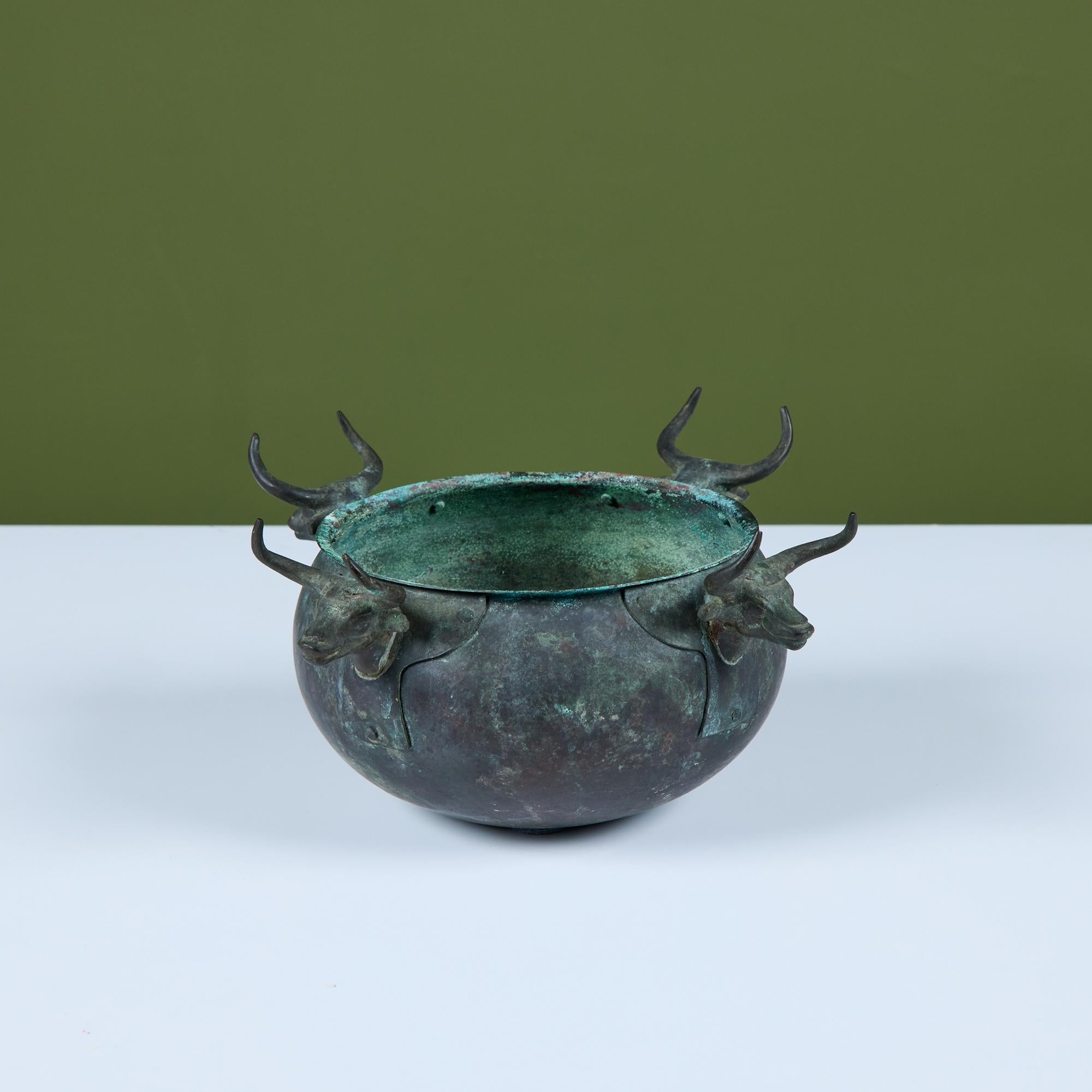 Cuenco de bronce patinado verdigrís con cuatro cabezas de toro montadas alrededor del borde que sirven de decoración y asas. Marcado 