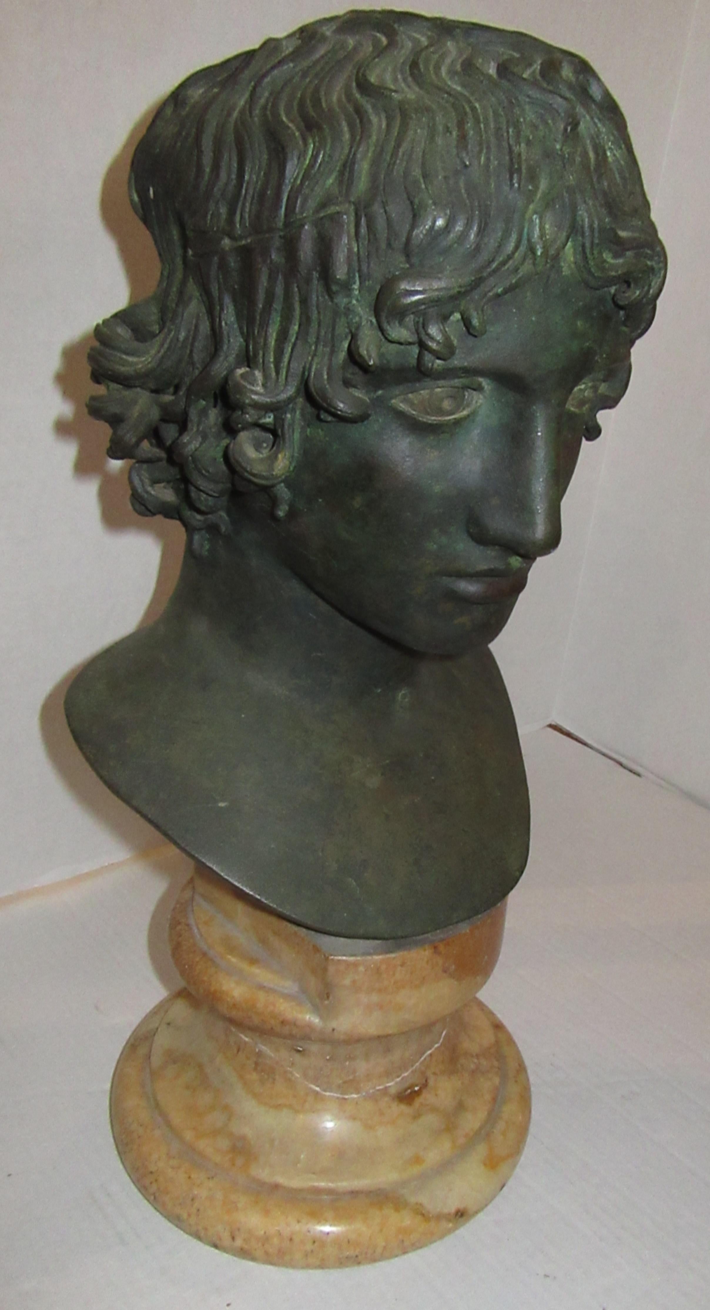 A patinated bronze bust of apollo attached to a marble base. From the collection of Lord Vincent Constantine at Cross Hall Manor.