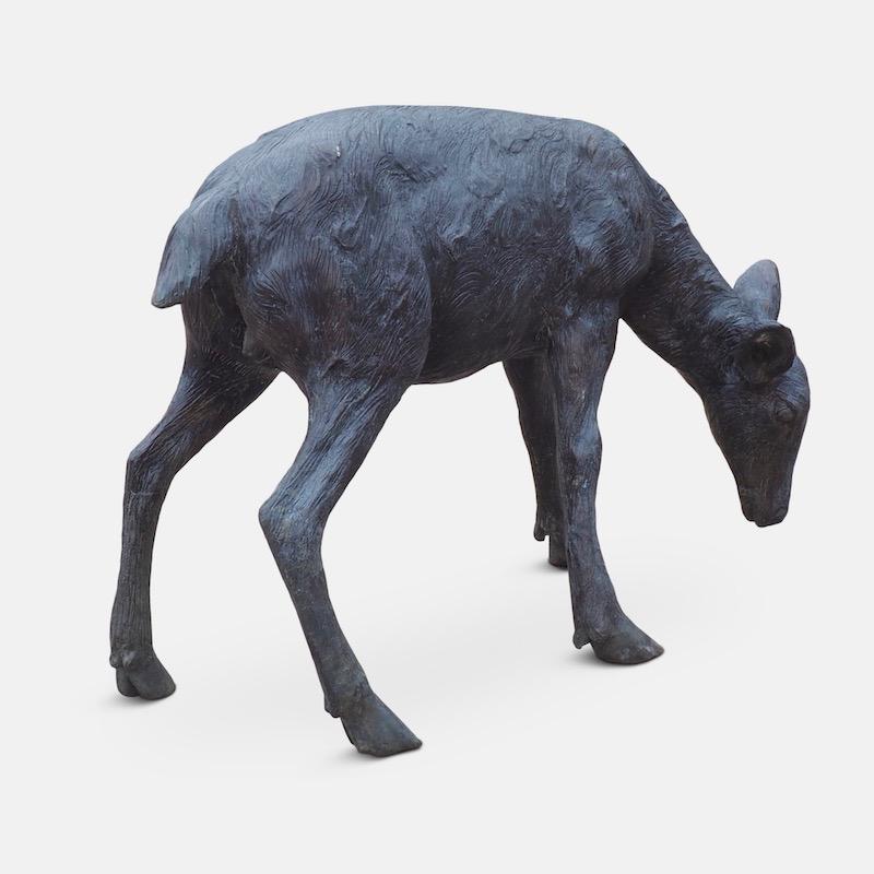 Cast bronze sculpture of a grazing Fawn. A charming representation of a young deer with a textured finish. Beautiful ornamentation for outdoor or indoor display.