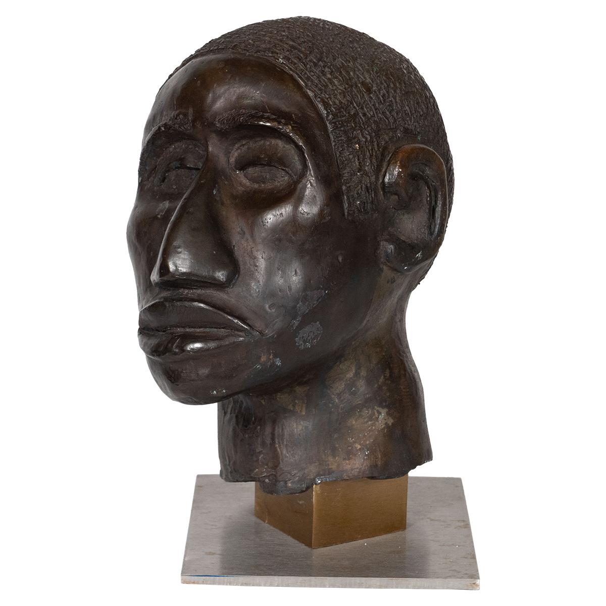 Cast bronze sculpture of a man's head on mixed metal base.