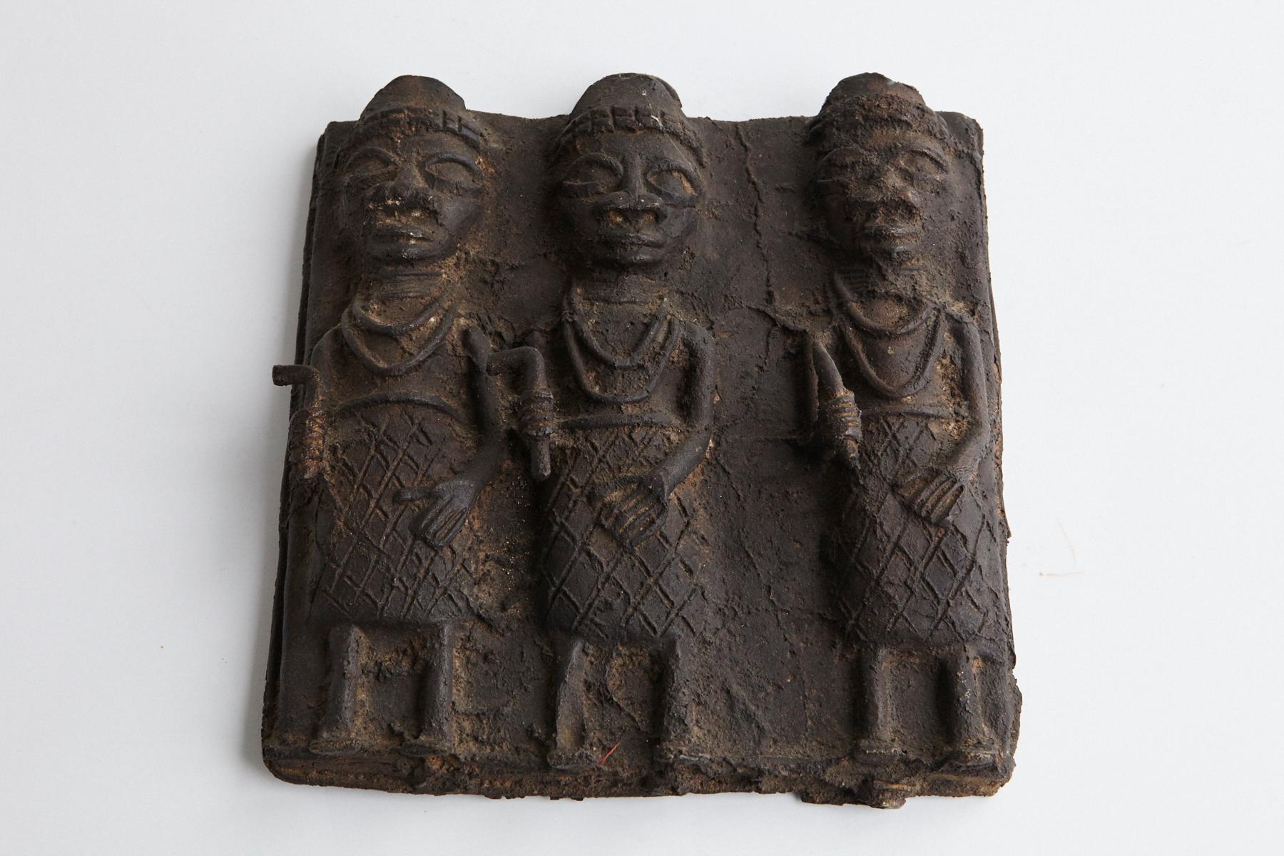 Intriguing cast bronze relief plaque from Benin, showing three guardians.
The plaque was modeled after ancient Benin bronzes but was made in the 20th century. The plaque is cast in bronze using the lost wax process.

The numbers are the inventory