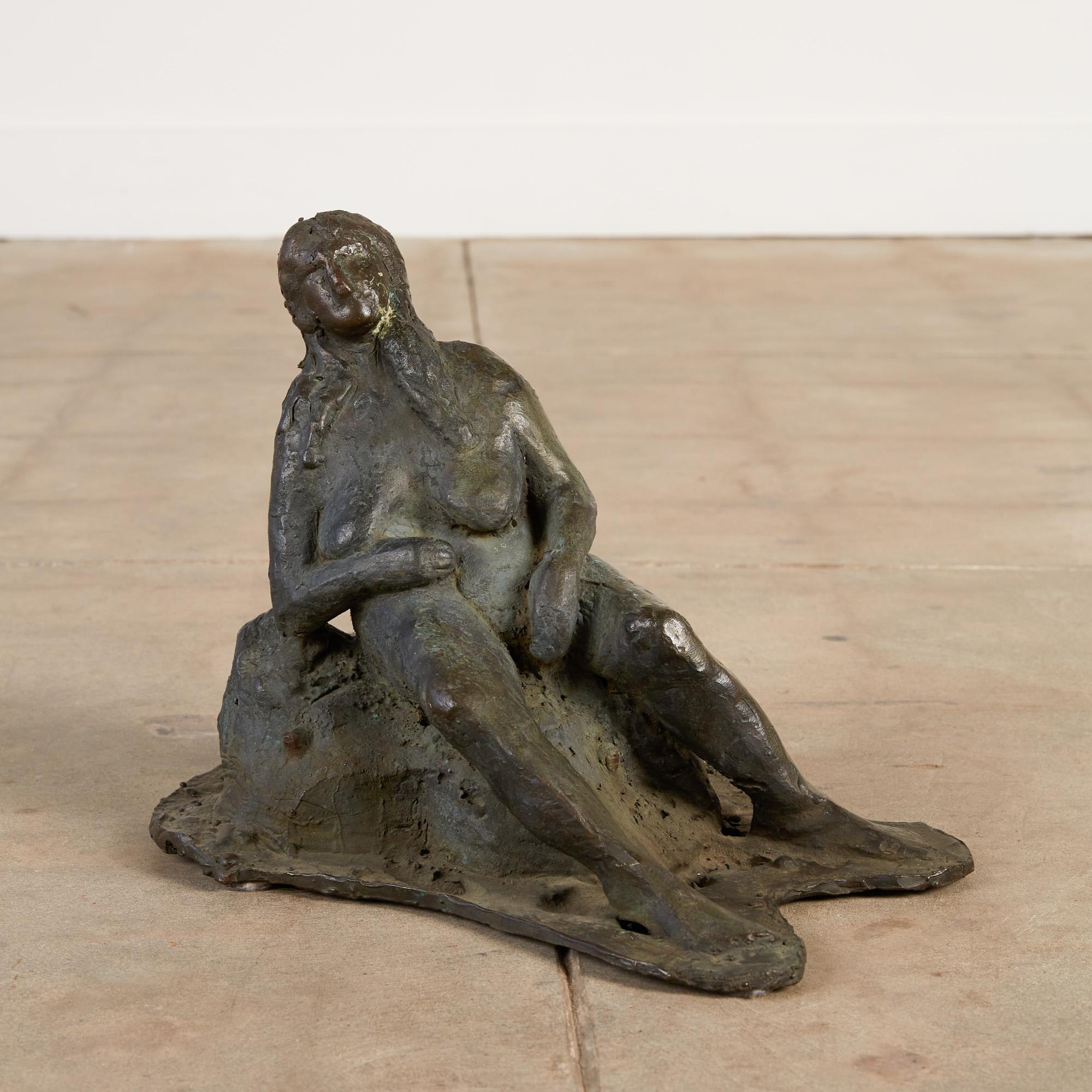 Cette sculpture en bronze coulé représente une femme, capturée dans un moment où elle vient de terminer une baignade dans son lac préféré. Elle contemple la vue, allongée sur un rocher, tandis qu'elle sèche suffisamment pour pouvoir se rhabiller et