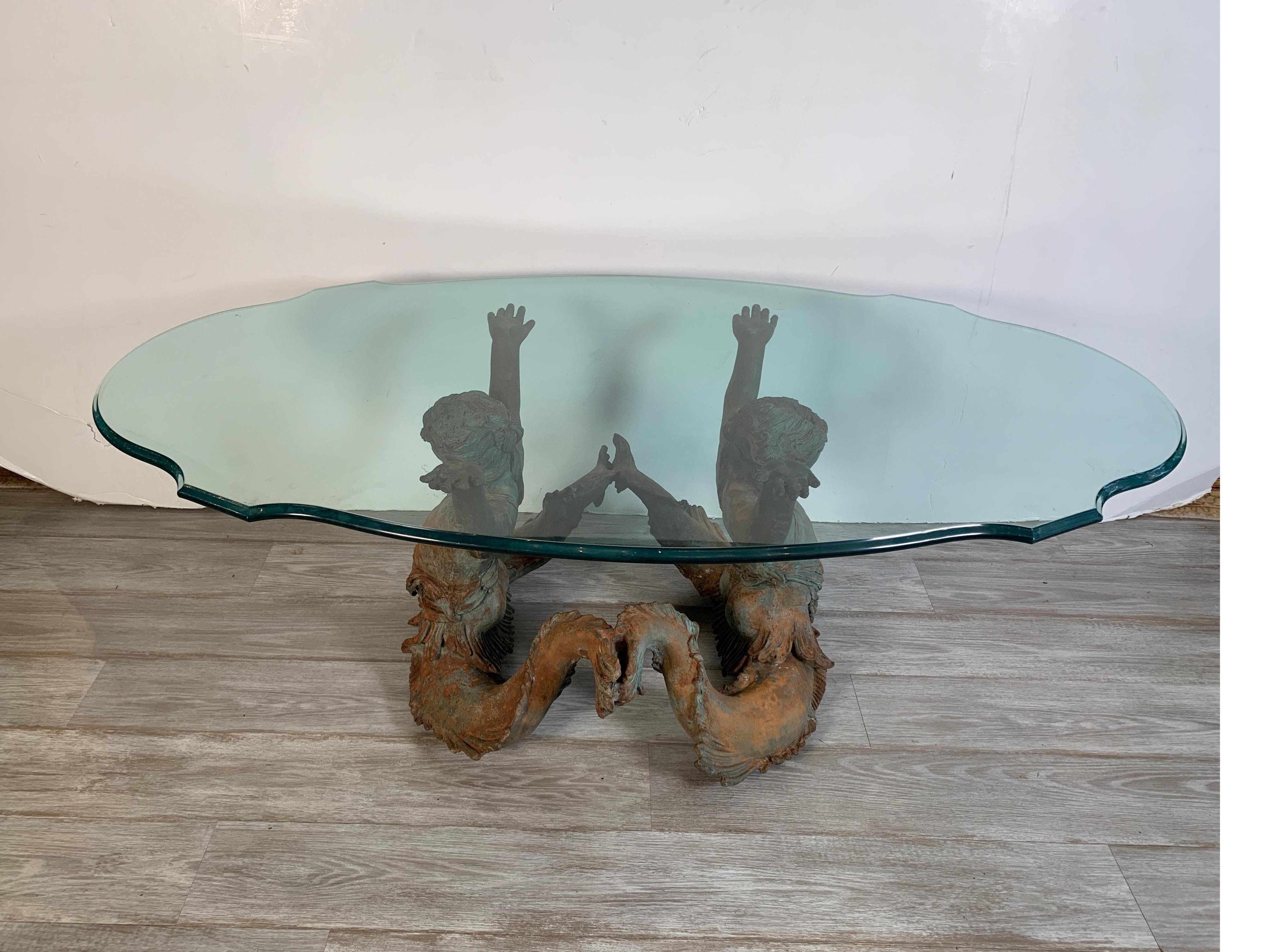Finely cast bronze figural coffee table base with a beveled glass top. The base consists of two jovial figures of sea nymphs, finely detailed with an intentional weathered finish.

Tabletop dimensions: 30