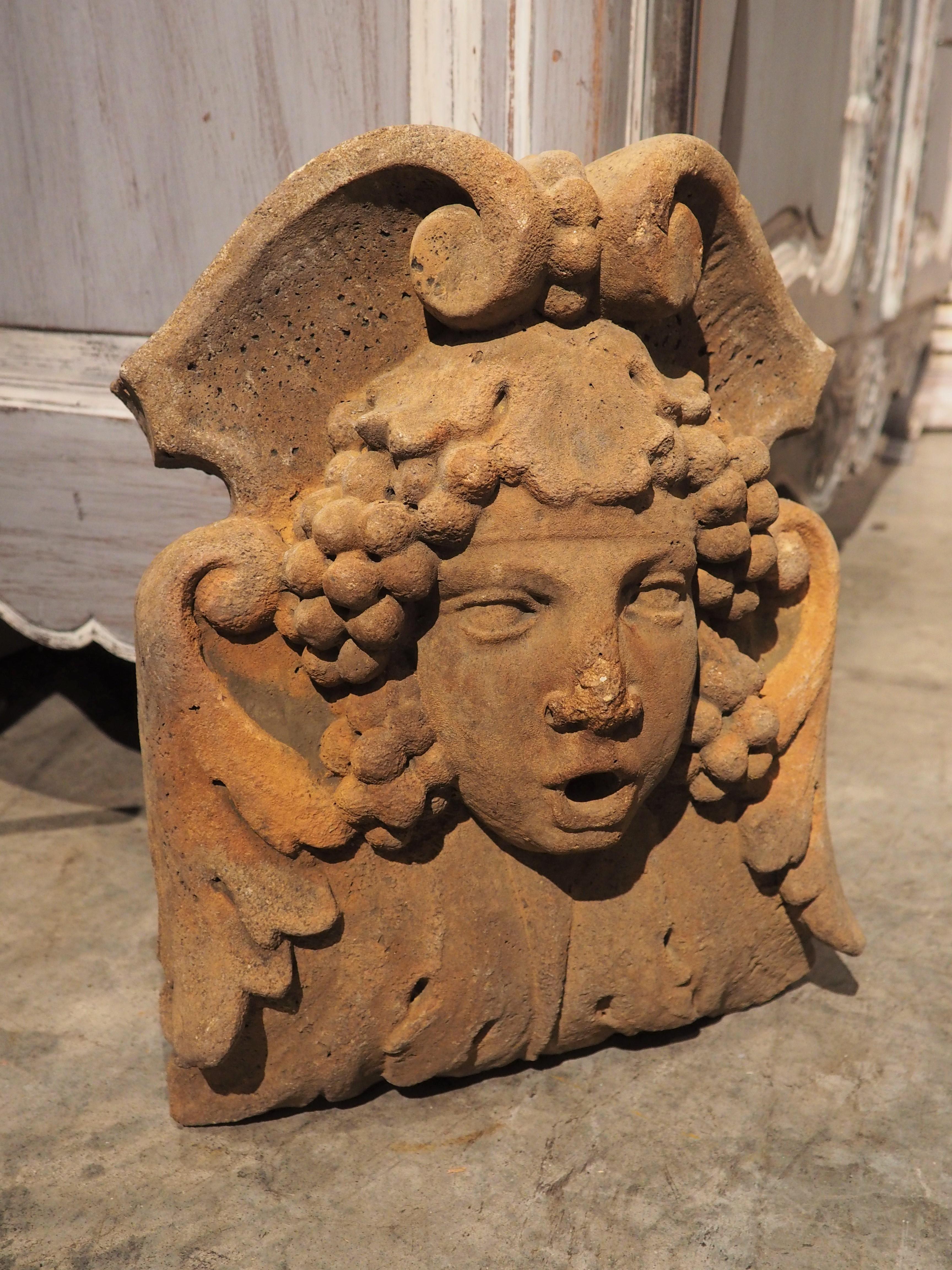 Bacchus, the Roman god of winemaking, is the subject of this small fountain mask element/spout; his Greek counterpart is known as Dionysus. Cast from reconstituted stone in France, the mascaron has been finished with an ochre color, but has