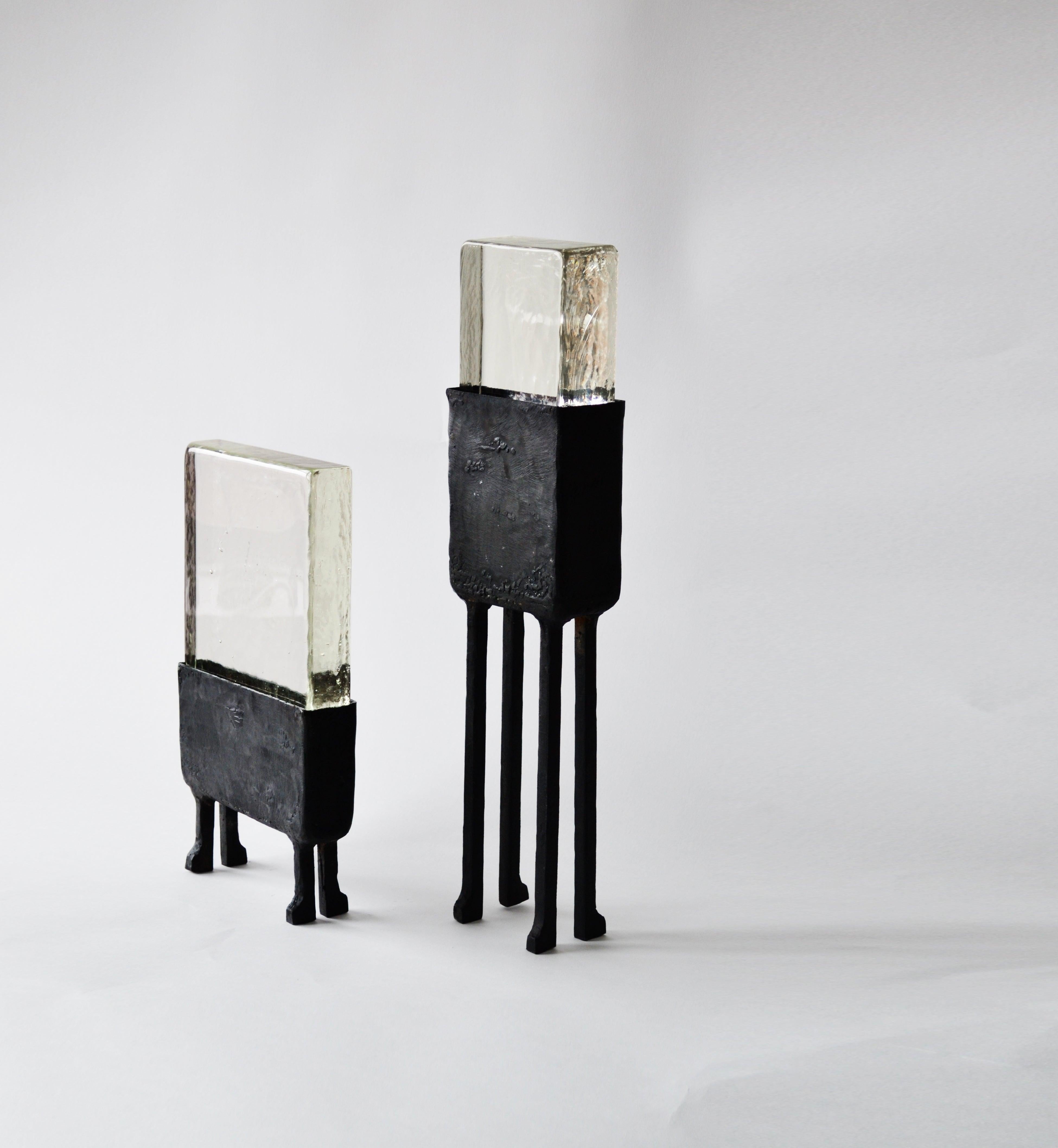 Cast glass and blackened steel are combined to become a striking table lamp. Unusual geometries and heavy material textures make this lamp very special and one of a kind.

Materials: Blackened steel, cast glass, led lighting

Dimensions: 20