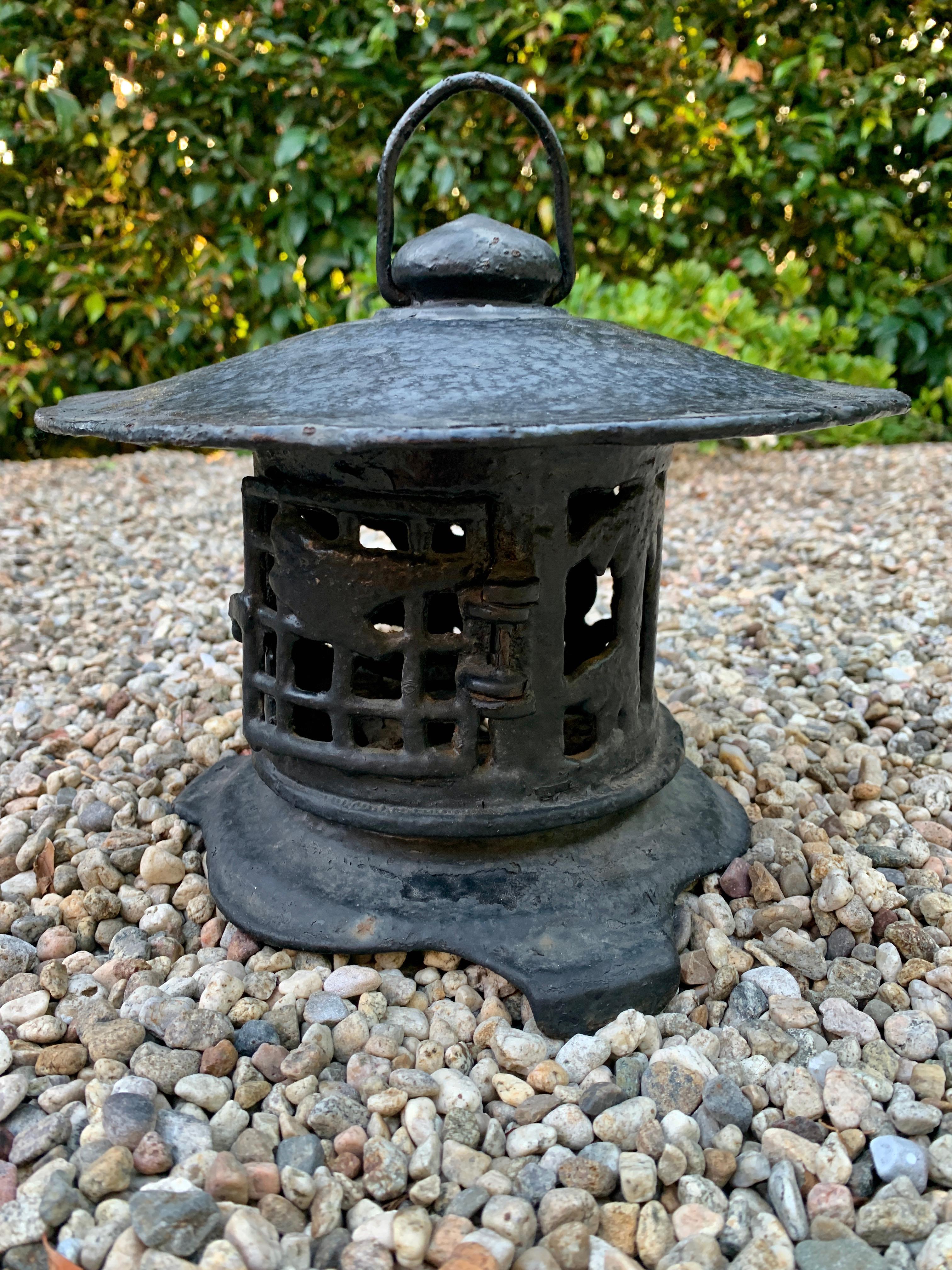 A compliment to any garden or walk way, this wrought iron lantern has an asian inspired design and is very heavy and substantial. The piece has a door that opens for a candle or adding another light source.