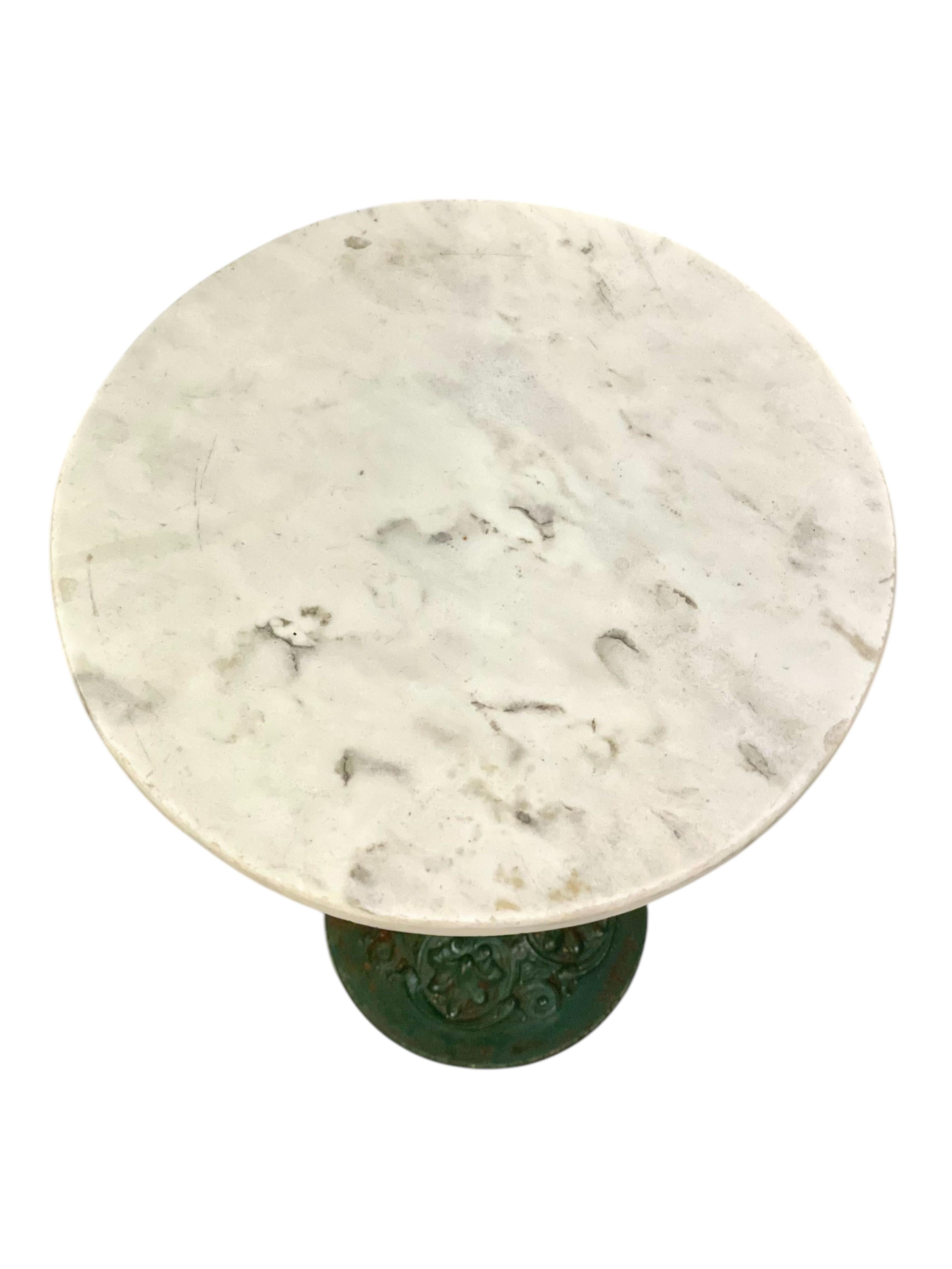 Bring timeless Parisian charm to your space with this authentic 19th century French bistro table, featuring a solid white marble top and an intricately detailed cast iron base. Originally used in French cafés and brasseries, this petite yet elegant