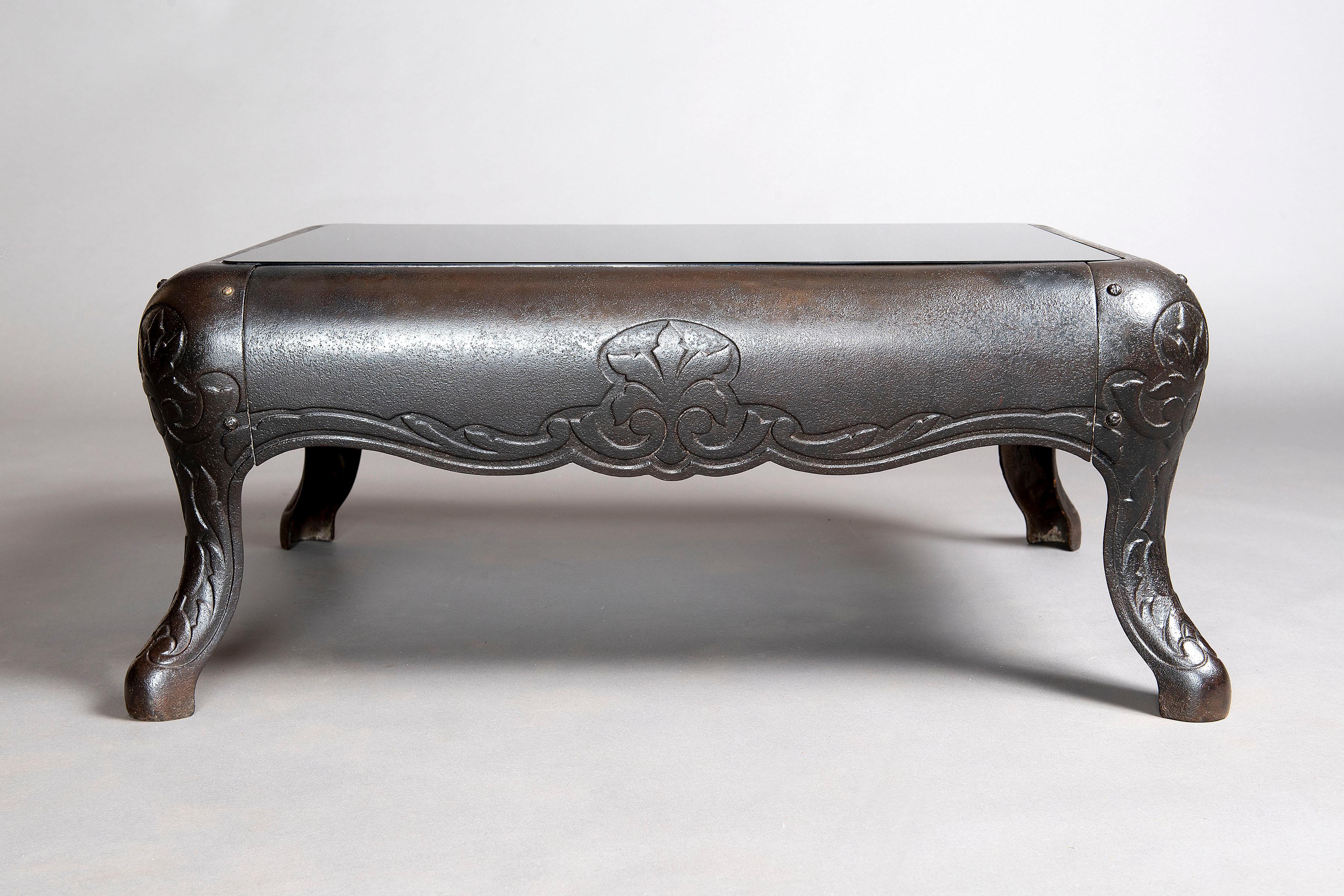 Repurposed antique stove base transformed into a one of a kind coffee table with smoke gray glass.
The cast iron coffee table takes it's foundation from the past and is modernized with the translucent gray inset glass.