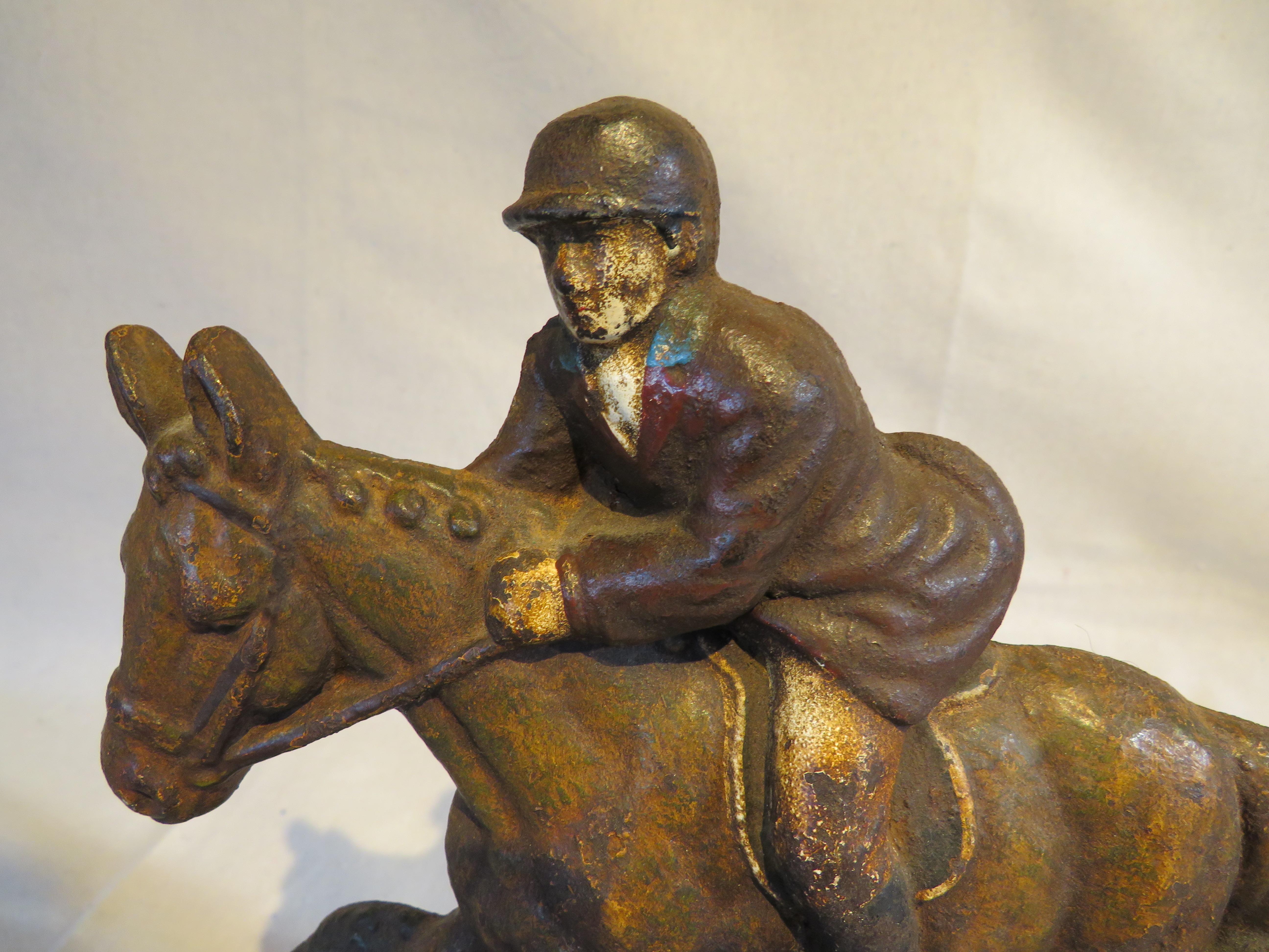 Sizeable 19th century cast iron doorstop of a man outfitted in equestrian gear jumping a horse over a gate. With vestiges of original painted surface throughout.