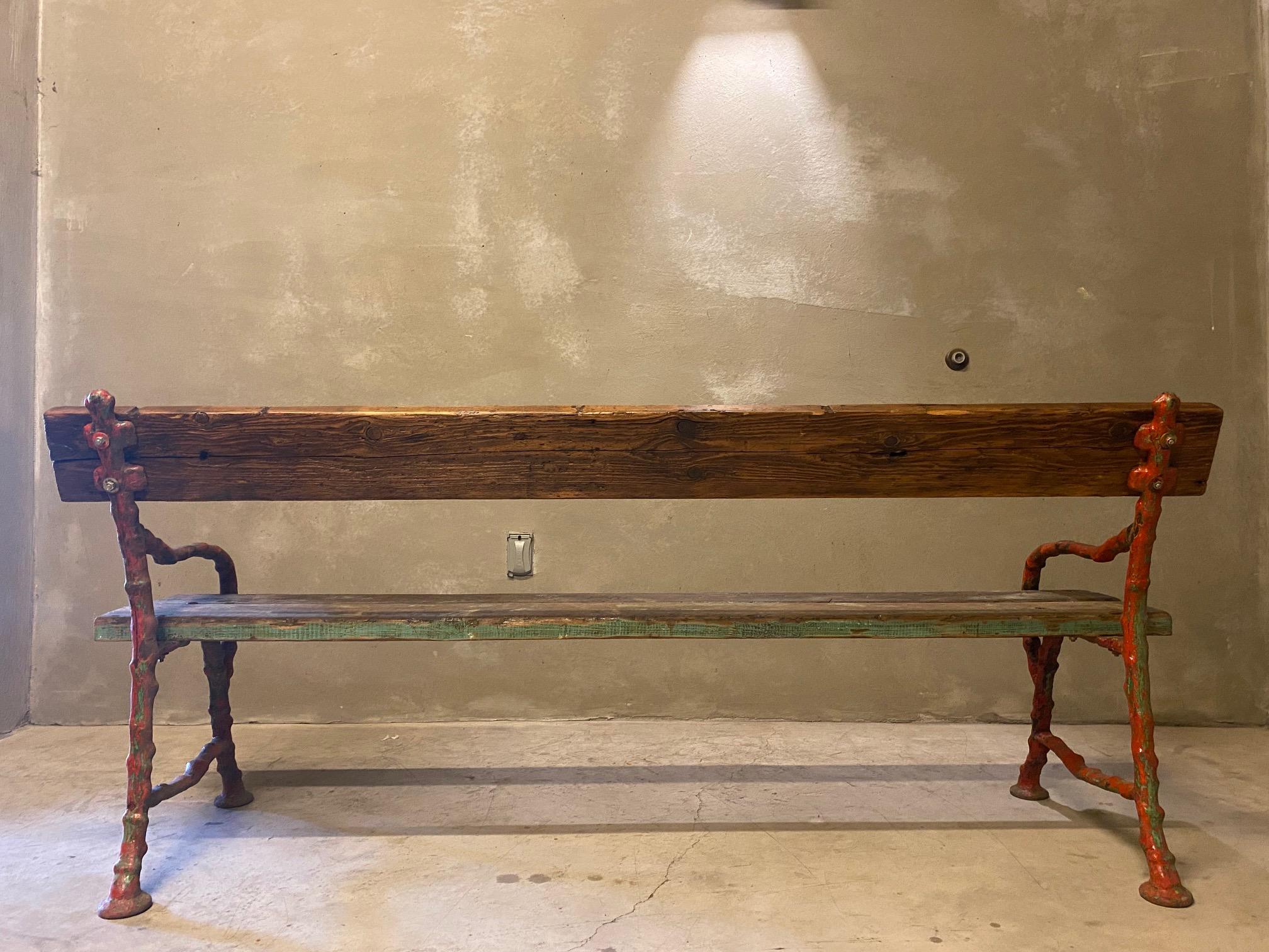 Cast iron faux bois bench with wooden plank seat and back.  Painted red heavy gauge cast iron frame supports thick wooden planks with remnants of green paint for authentic patina.  France, late 19th to early 20th century