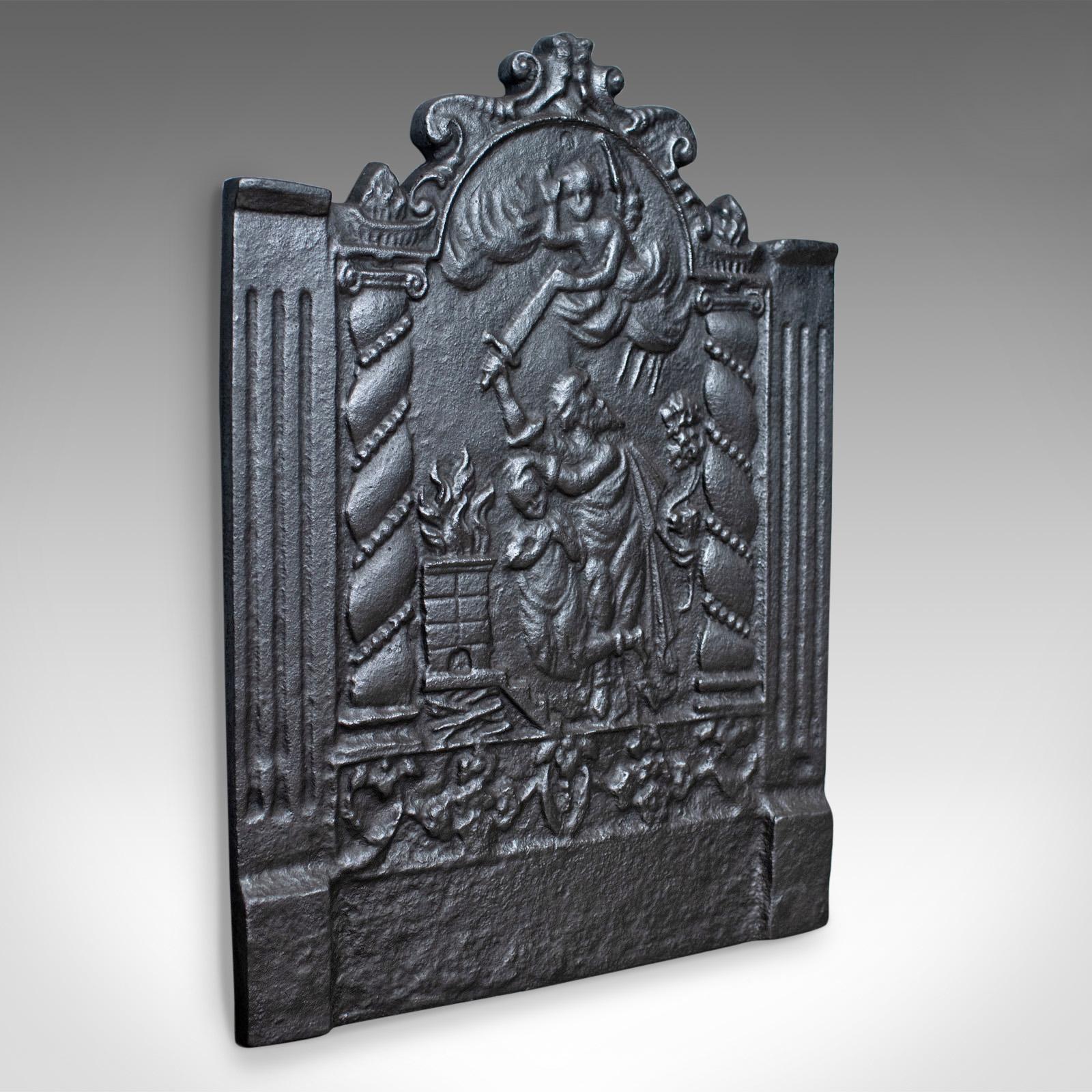 This is a cast iron fire back, a 17th century revival fire plate featuring figures and angel, late 20th century.

A most pleasing fire back presented in good condition
Crafted in heavy cast iron
Displaying figures with an angel holding back a