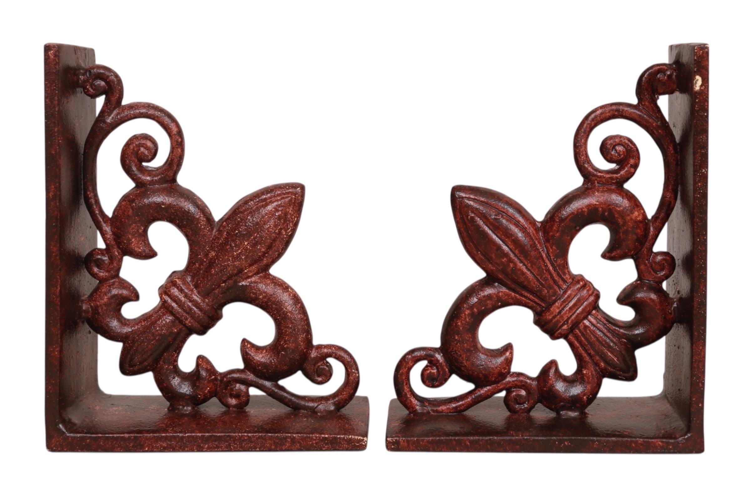 Una coppia di pesanti fermalibri in ghisa. Le forme a L sono decorate con un Fleur De Lis incastonato in volute, angolate per dare l'aspetto di staffe da parete francesi. Rifinito in un colore marroncino screziato. Dimensioni per ogni fermalibri.
