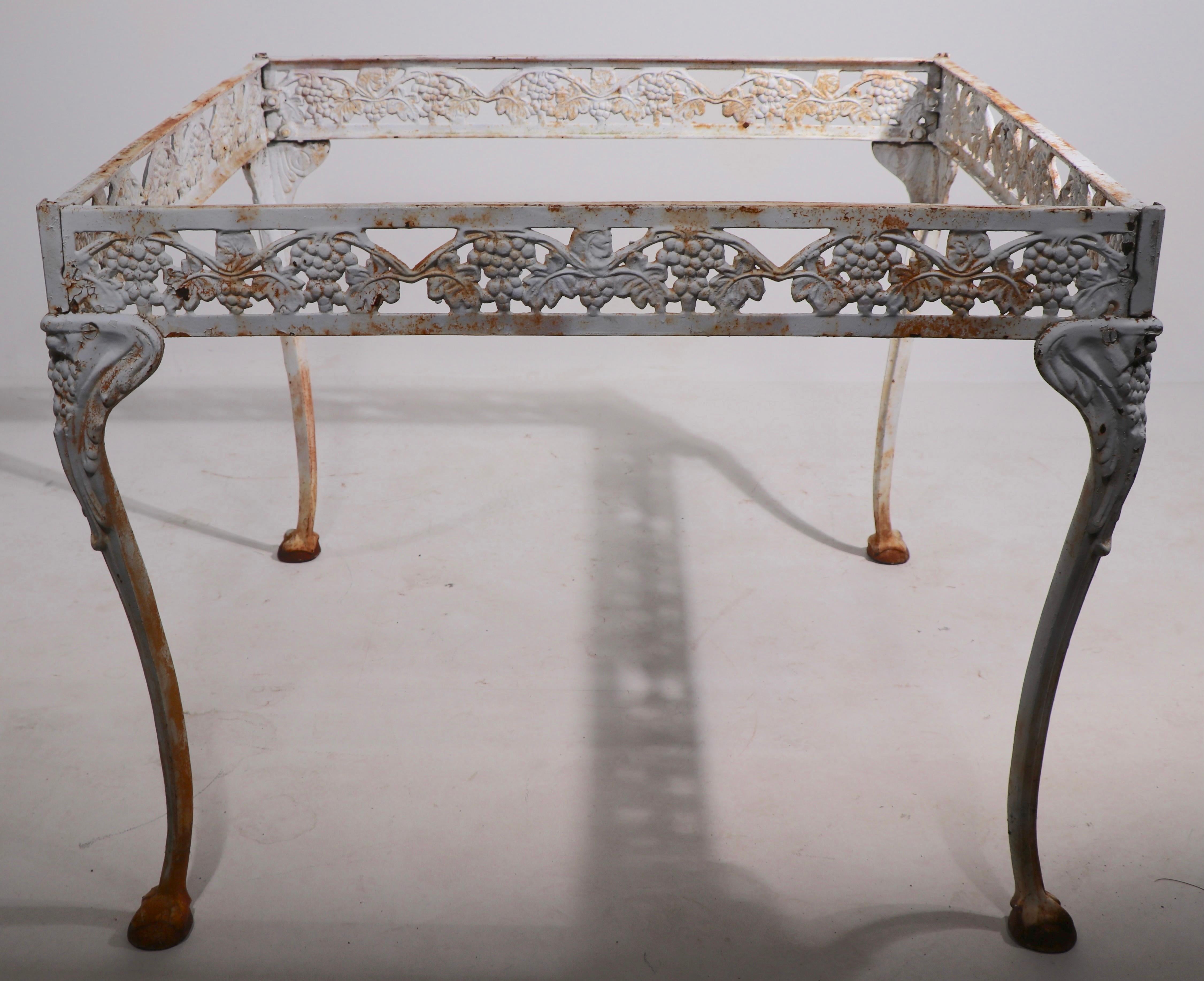 Decorative and charming cast iron and glass diminutive dining table by the Atlanta Stove Works company. The table is executed in the Victorian style, circa mid 20th C. Structurally sound and sturdy, the finish shows rust and wear to the paint