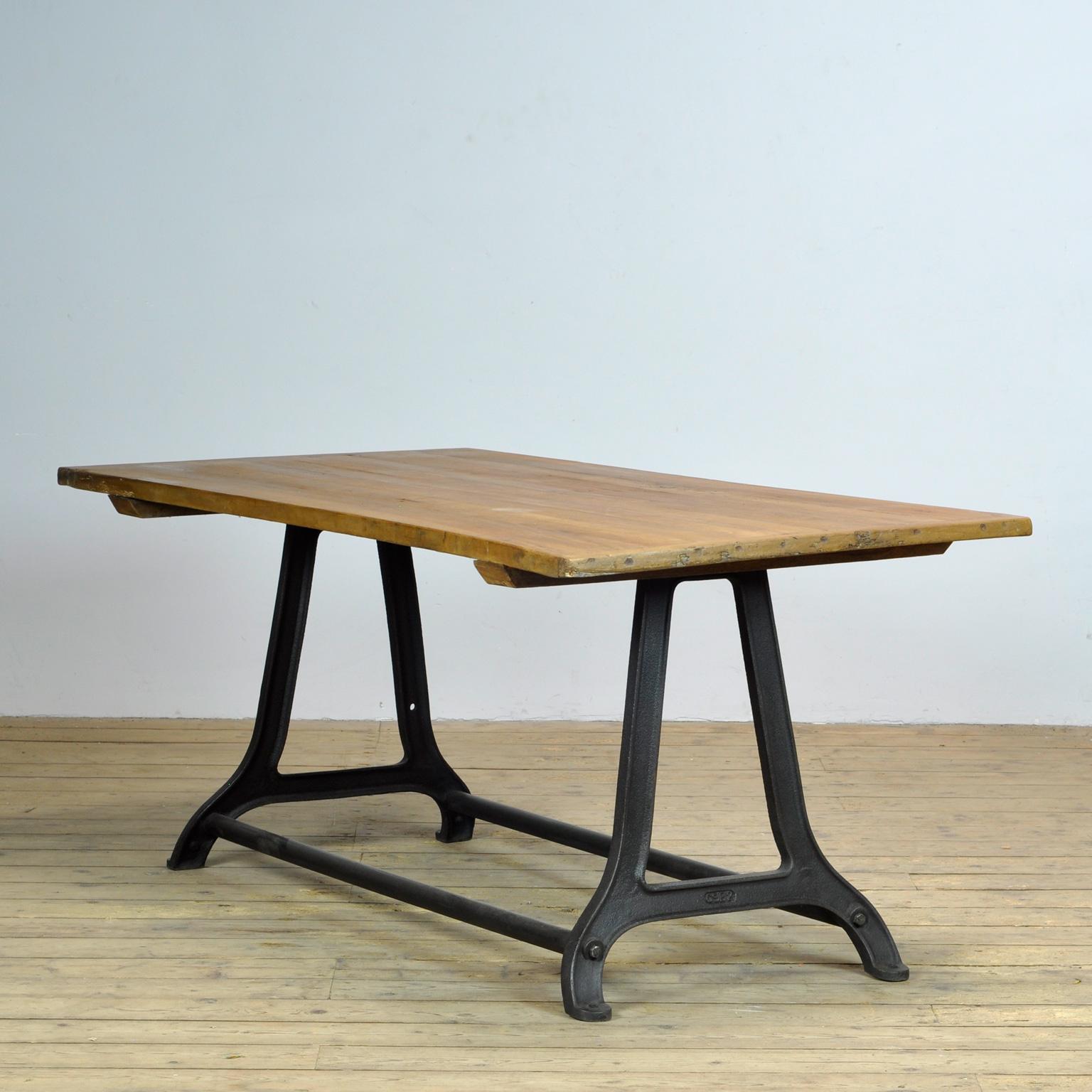 La table est fabriquée à partir d'une ancienne base de machine industrielle en fonte et d'un vieux plateau en pin.