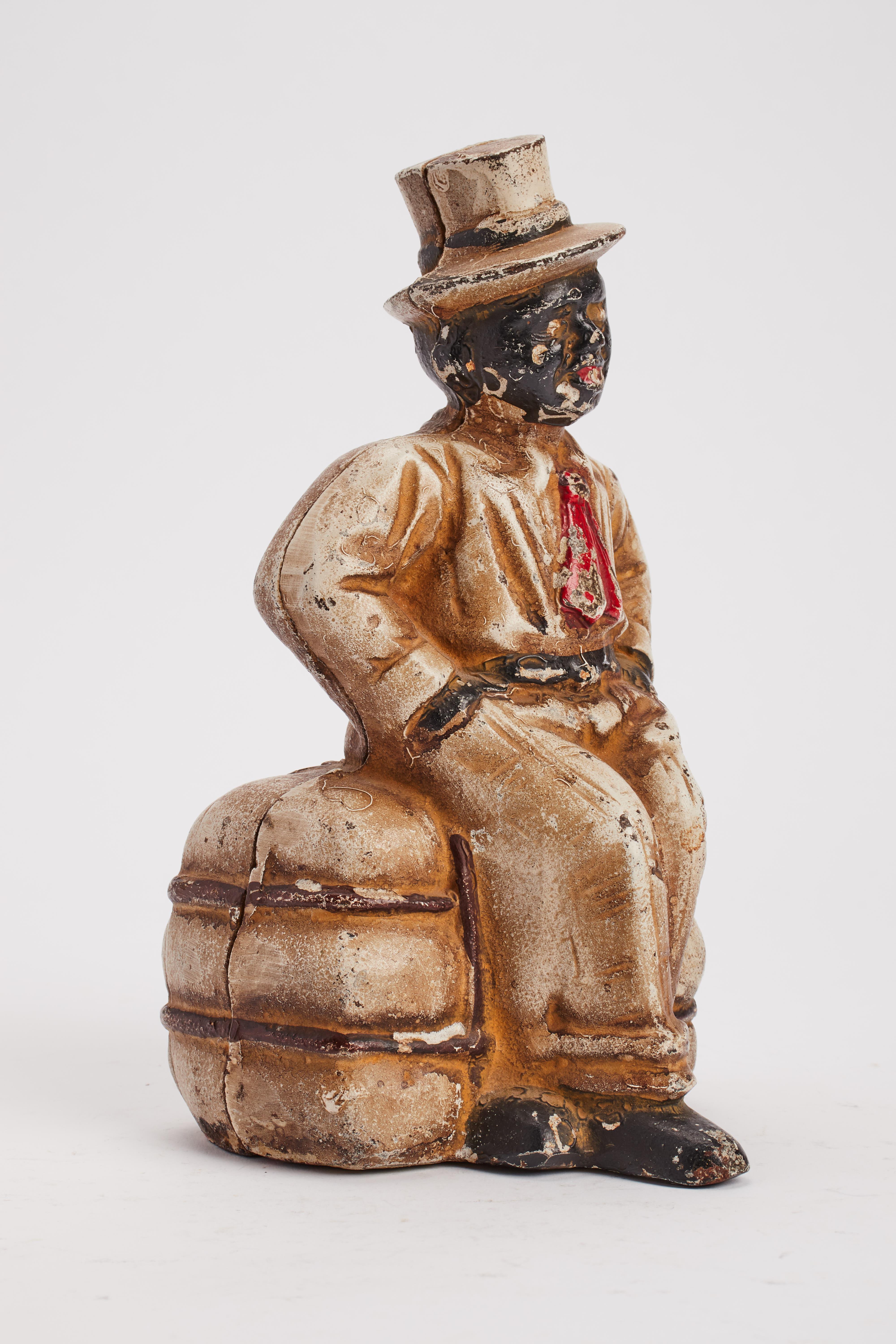 Bemalte gusseiserne Spardose mit der Darstellung eines Afroamerikaners, der auf einem Baumwollballen sitzt. USA 1920 ca.