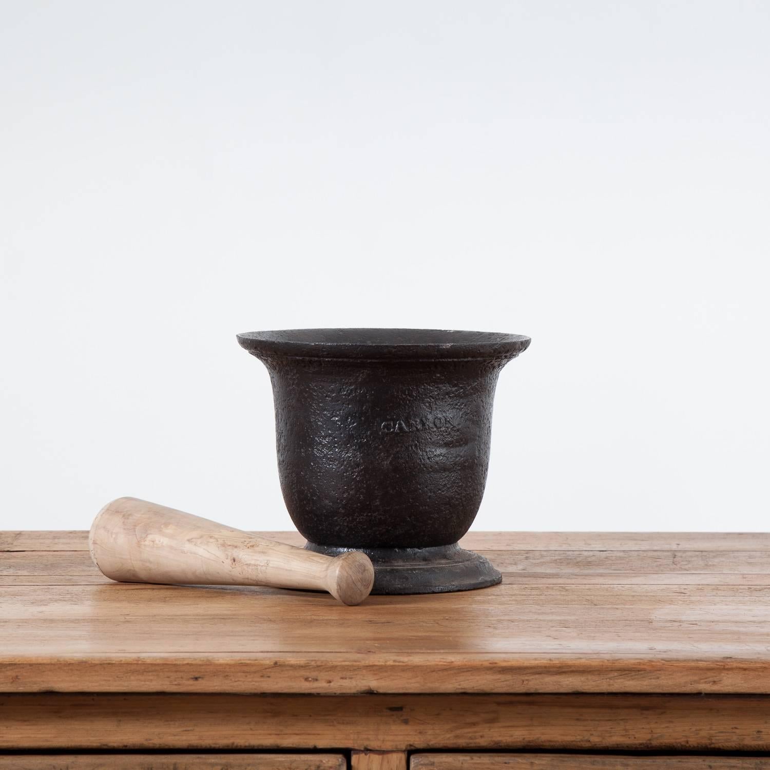 Very nice cast iron pestle and mortar with a lovely replacement wooden pestle.

This piece has been stamped Carron.

The Carron Company was an ironworks established in 1759 on the banks of the River Carron near Falkirk, in Stirlingshire,