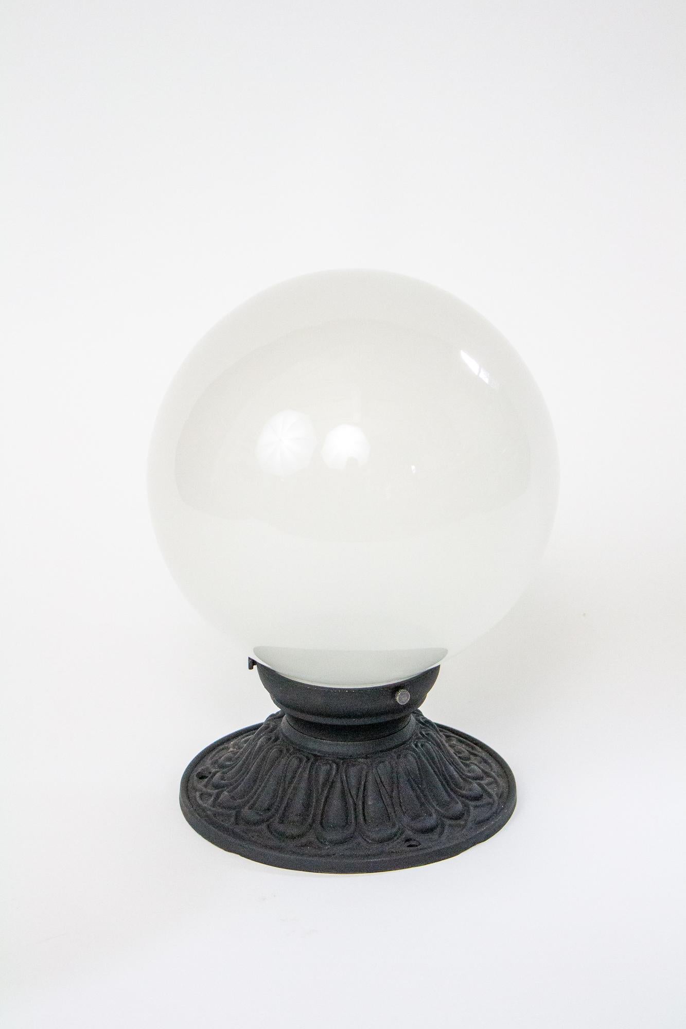 Classic porch light. Cast iron base with scalloped details, painted in a matte black. Single porcelain socket. Interior sandblasted hand blown glass globe. New, made in the same fashion as pieces made in the early 20th century. Max wattage 150W.