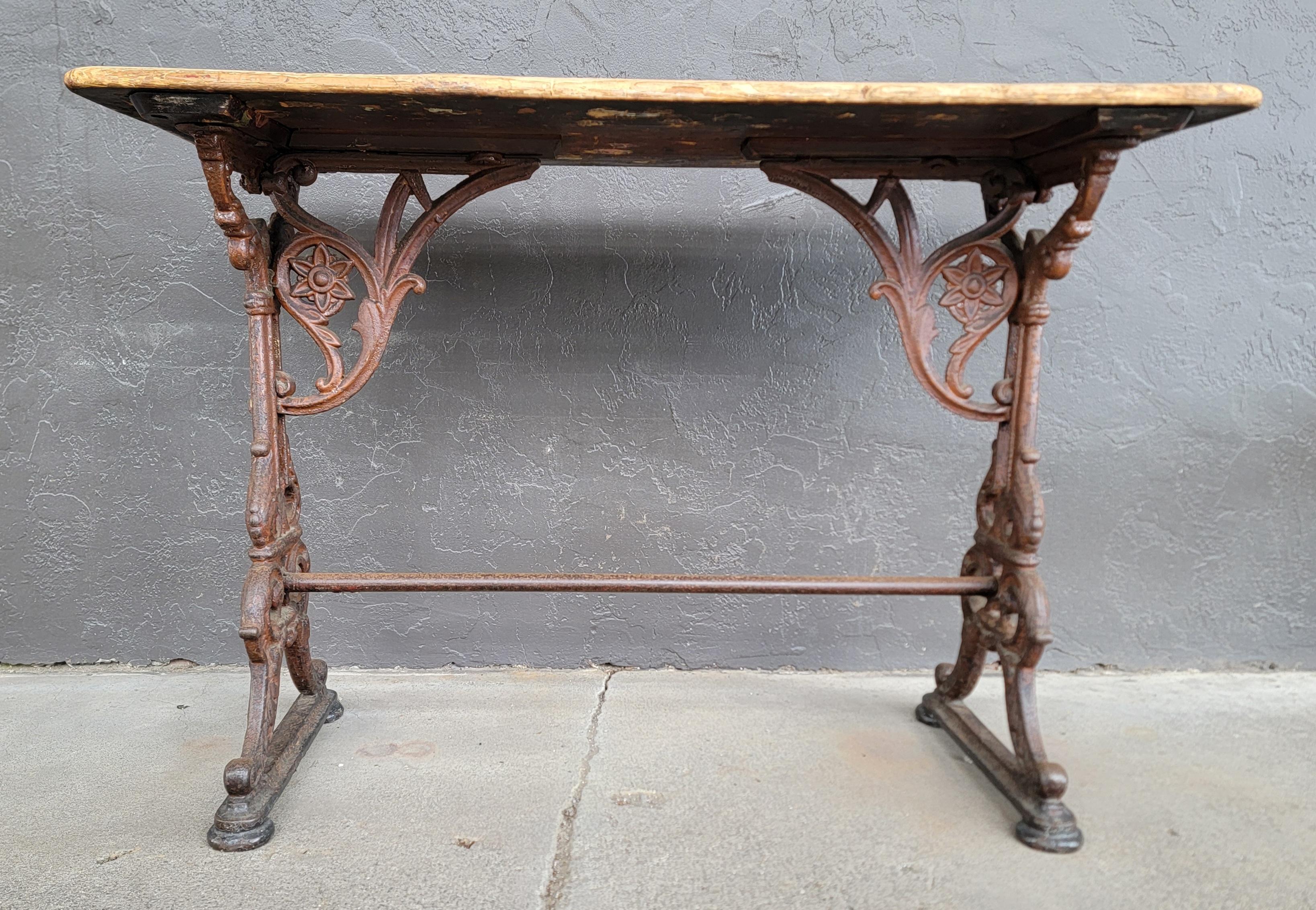 Rare table de pub en fonte de forme rectangulaire. Circa. début des années 1900. Moulage très détaillé avec plateau en bois peint d'origine. Finition rustique et industrielle. Peut être apprécié comme console, canapé, table de travail ou comme
