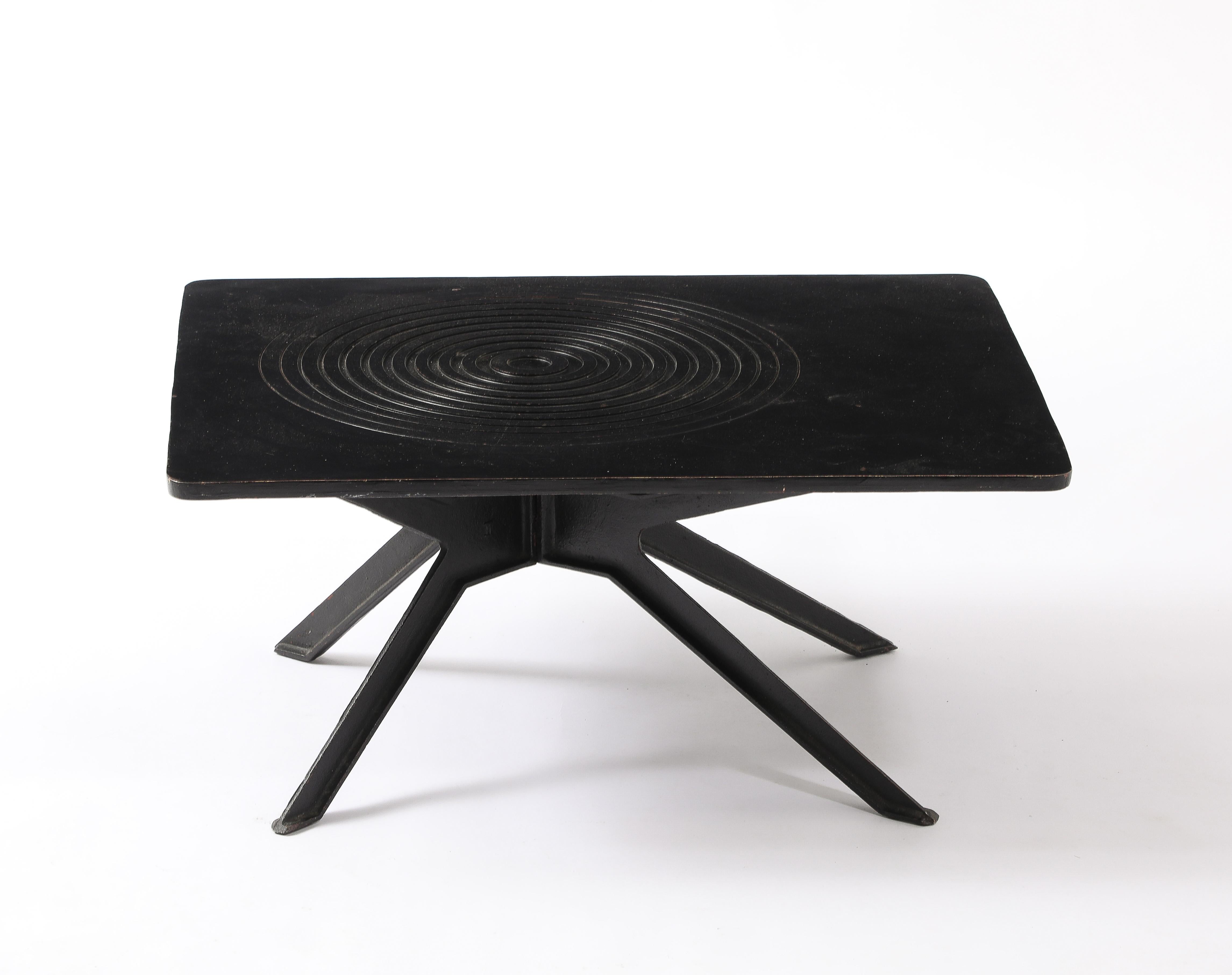 Table en fonte massive sur une base en croix, le plateau est orné d'un motif rappelant l'effet d'ondulation de l'eau.